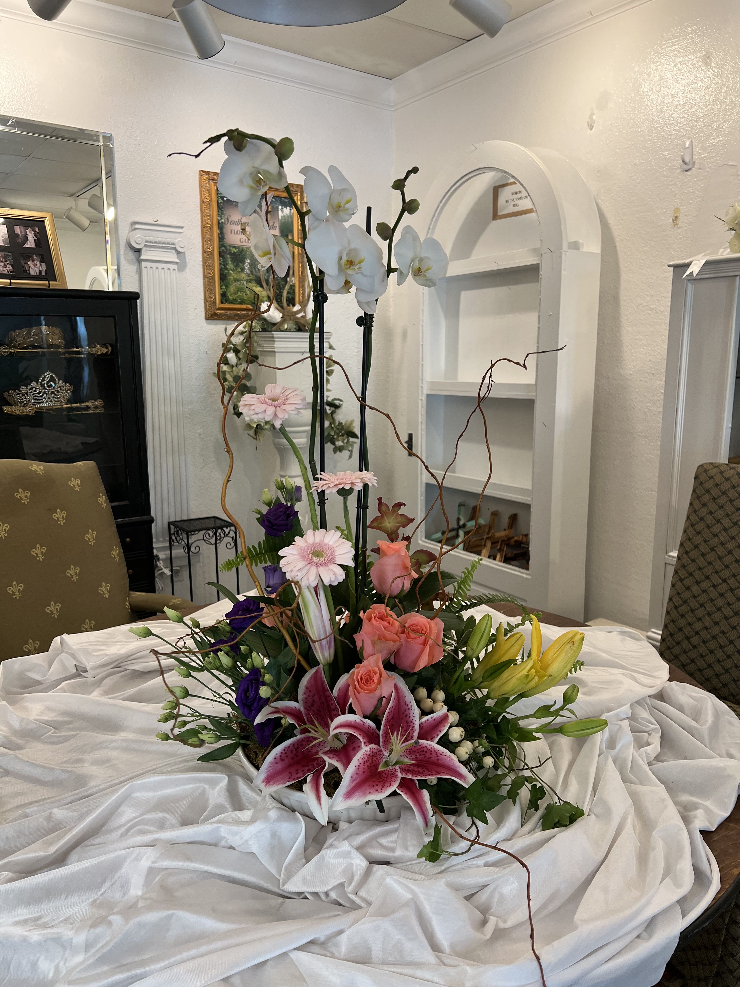 Tall floral arrangement with orchids, lilies, roses, and gerbera daisies