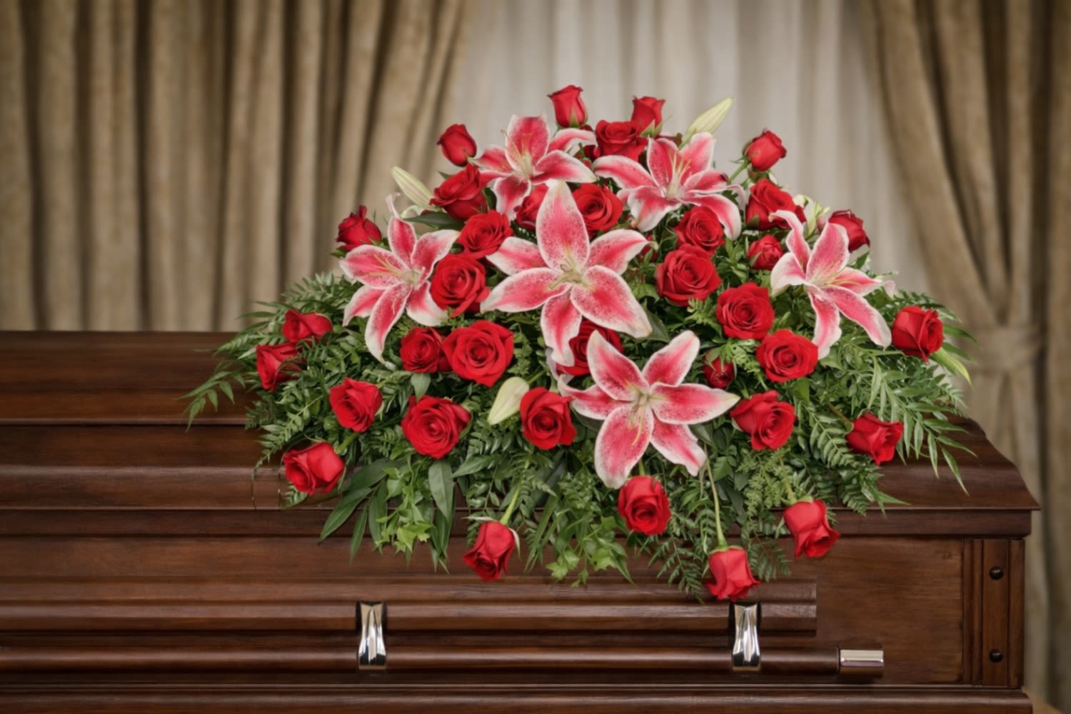 Dedication Of Love Casket Spray  - The Dedication of Love Casket Spray from FloralFabulous is a timeless and heartfelt tribute designed to express deep love, honor, and remembrance. This elegant arrangement features rich red roses paired with stunning pink lilies, beautifully accented with lush greenery for a soft cascading effect.  The combination of red roses and pink lilies symbolizes love, admiration, compassion, and enduring connection, making this arrangement especially meaningful for honoring a spouse, partner, or deeply cherished loved one. Designed to rest gracefully atop the casket, this spray creates a powerful and elegant focal point during funeral and memorial services.  The Dedication of Love Casket Spray offers a beautiful expression of sympathy, bringing comfort to family and friends while celebrating a life filled with love and meaningful memories.  FloralFabulous proudly provides funeral flower delivery and casket sprays in Round Rock, TX and the greater Austin area, helping families express heartfelt condolences with elegance and care.