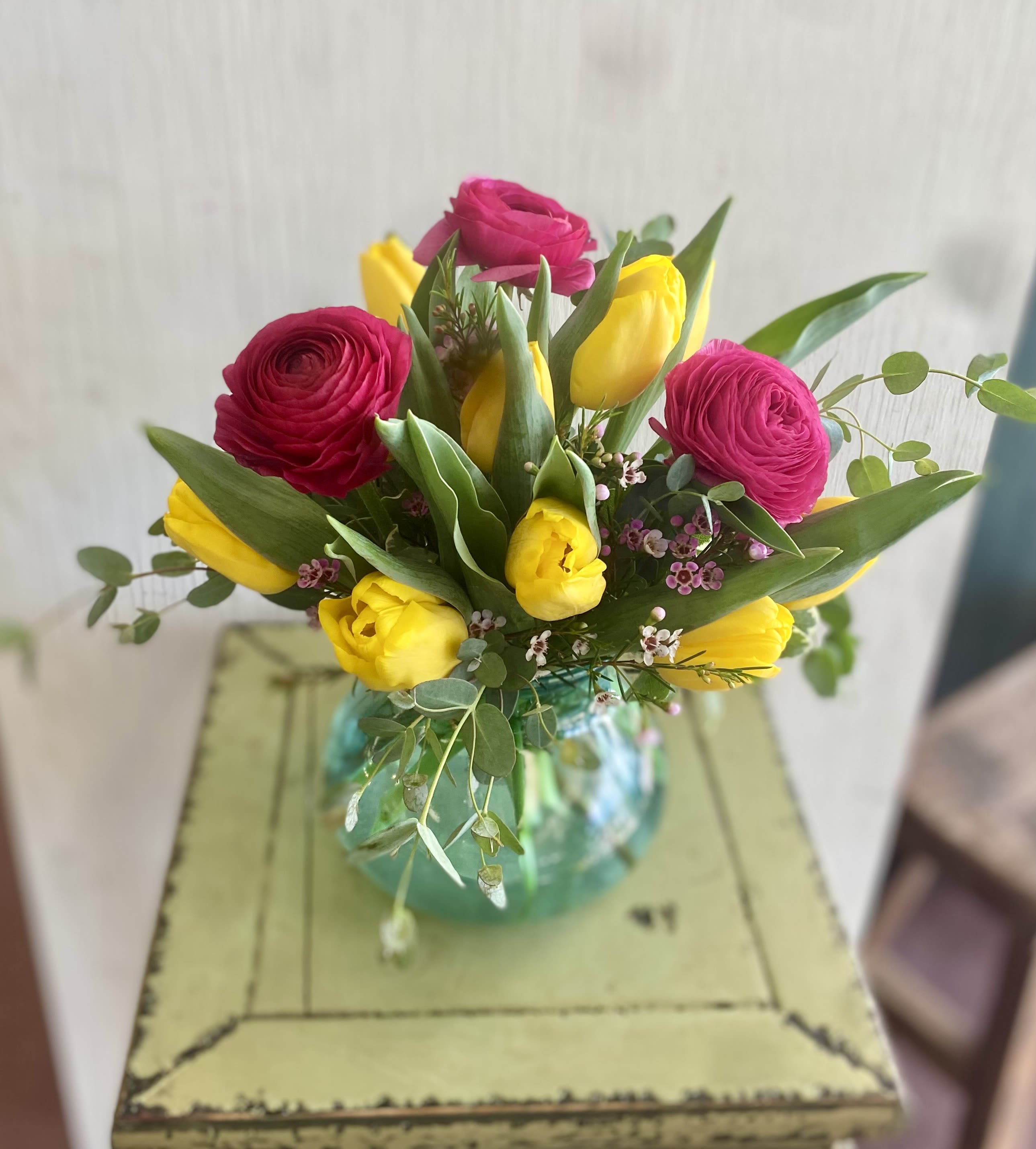 Bouquet of pink ranunculus and yellow tulips in a glass vase