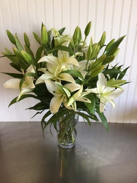 White lilies arranged in a clear glass vase