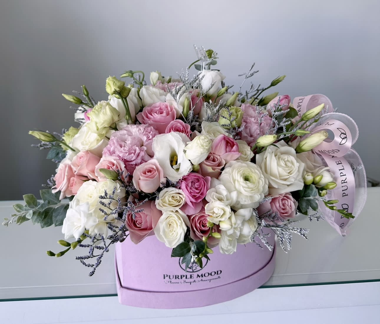 Cute heart box - Box size: approximately 11” x 11”  The Cute Heart is a soft and romantic design presented in a pastel pink, heart-shaped box. Featuring a dreamy combination of roses, lisianthus, calla lilies, and ranunculus, this bouquet blends white, cream, and blush-pink tones with delicate greenery for balance. Elegant yet playful, it’s the perfect gift for love, celebration, or simply to brighten someone’s day.    •    Premium roses, lisianthus, ranunculus, and calla lilies     •    Soft pink, blush, and white color palette     •    Arranged in a pastel pink heart-shaped box with ribbon     •    Ideal for anniversaries, birthdays, or “just because” surprises