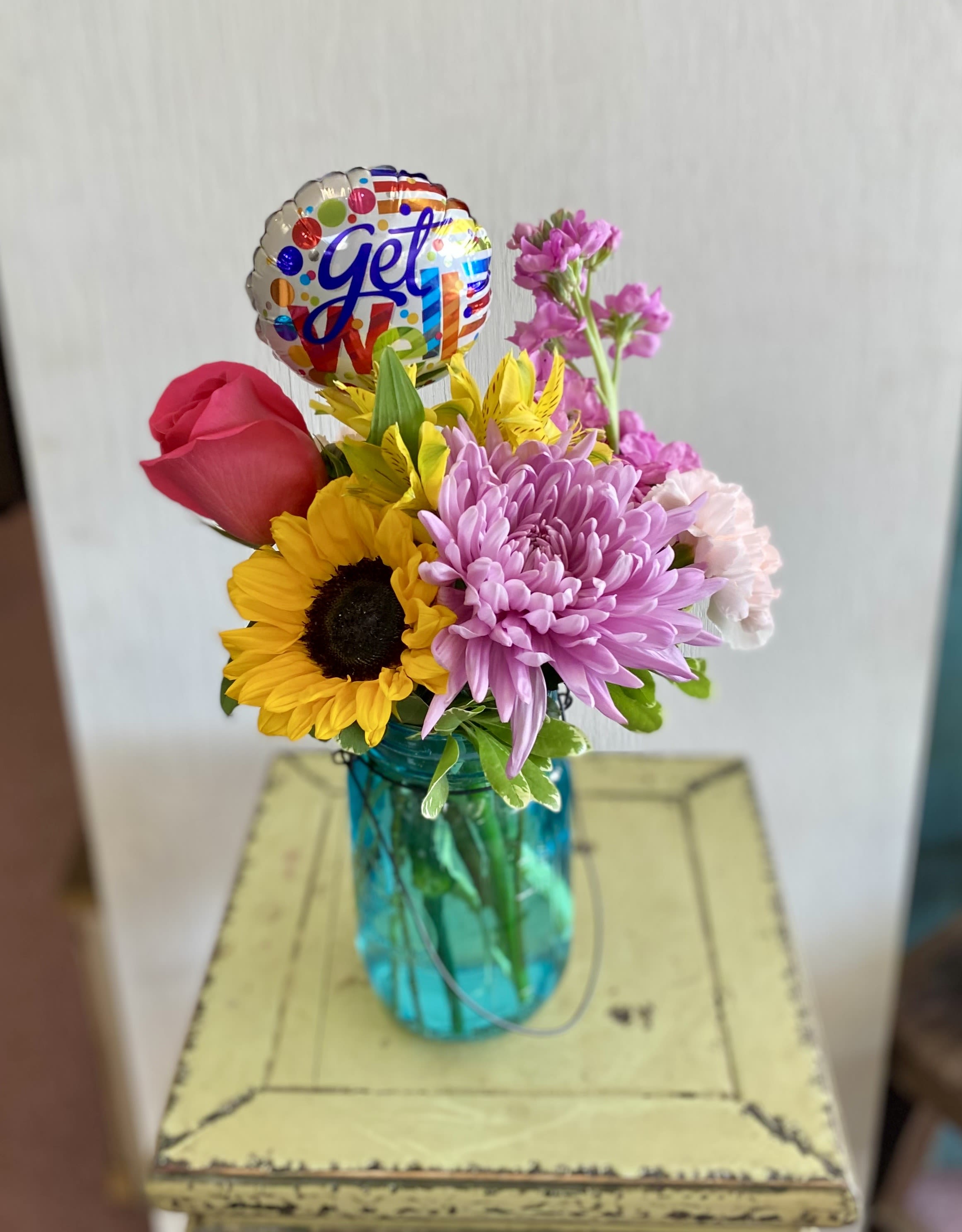 Mixed bouquet in a blue vase with a colorful balloon