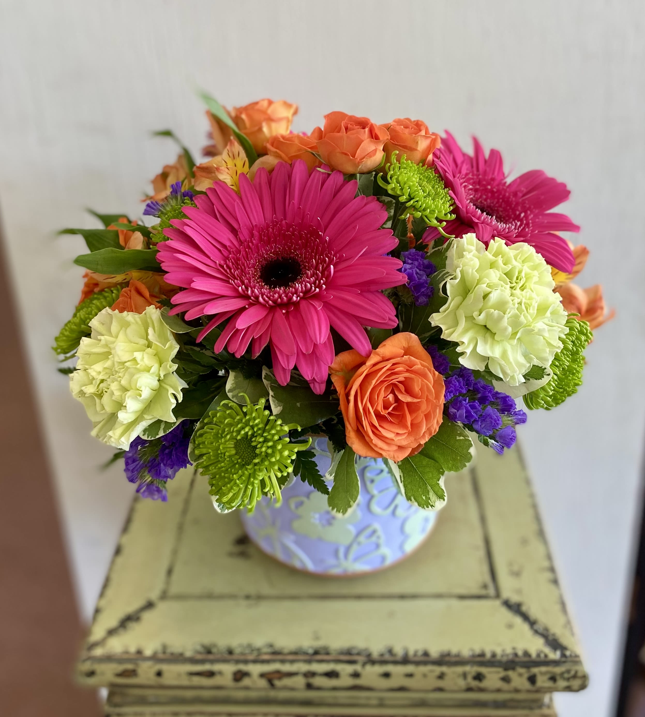 Bright mixed bouquet in a patterned vase with pink gerberas and orange roses