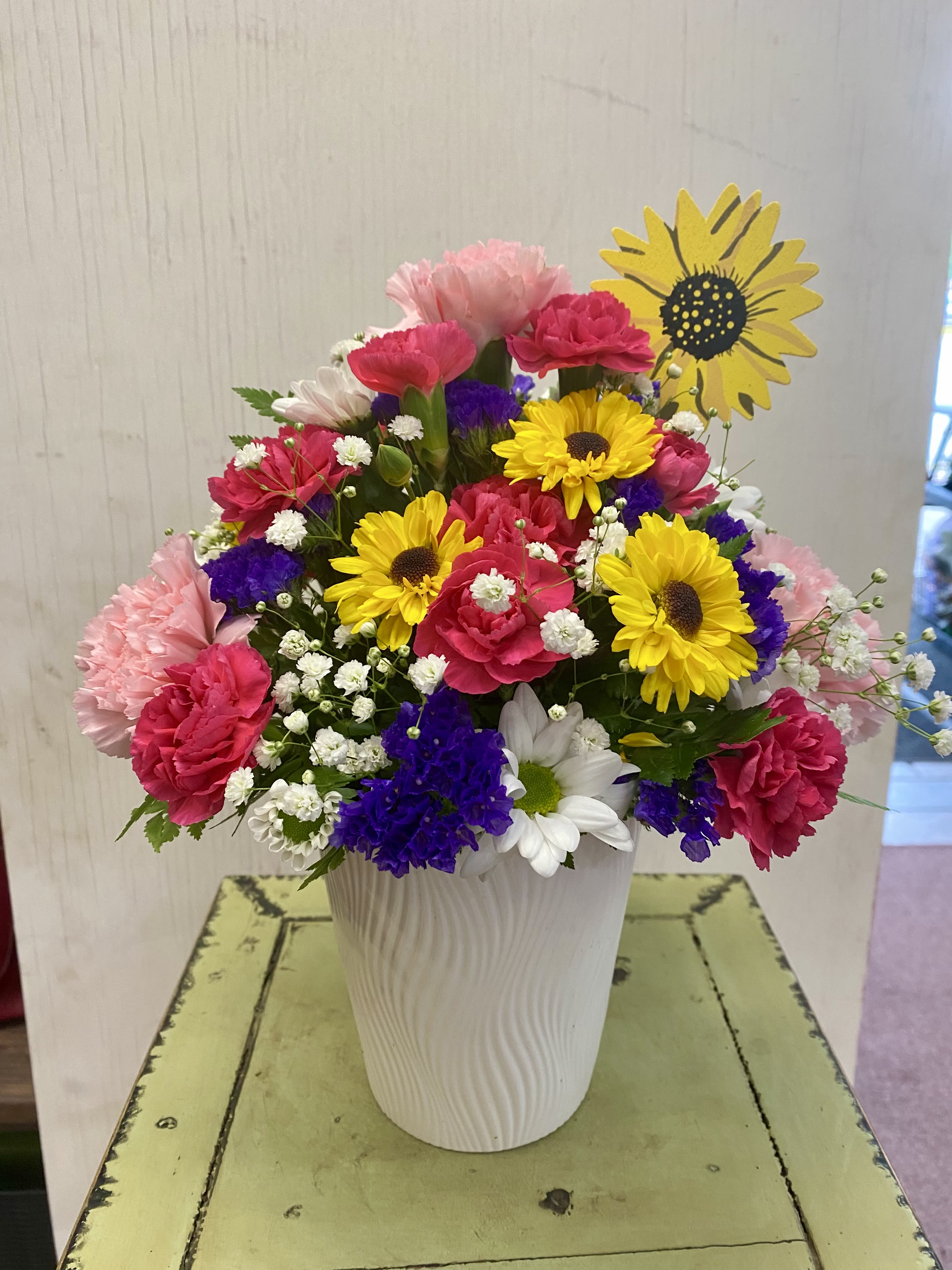 Colorful mixed bouquet in a white vase with daisies and carnations