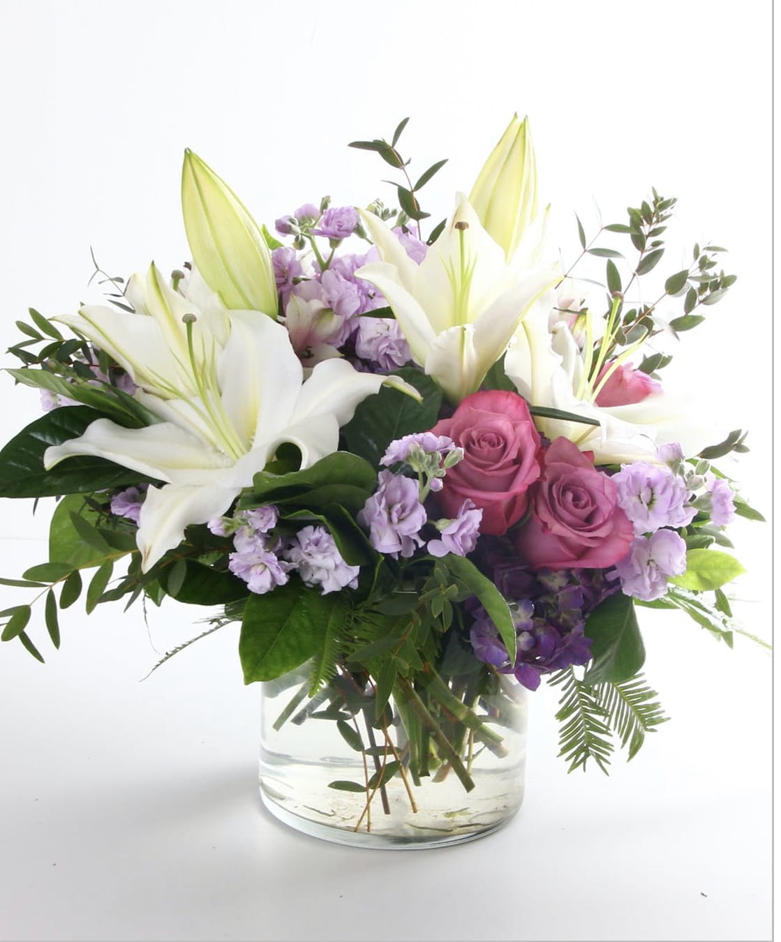 Bouquet of white lilies and pink roses in a clear glass vase