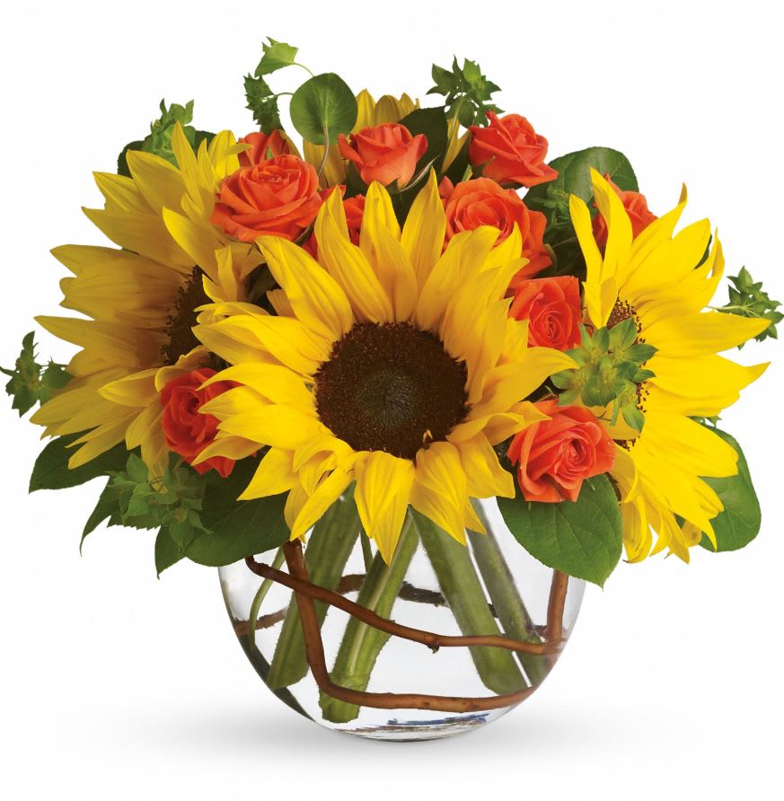 Sunflowers and orange roses arranged in a clear glass vase