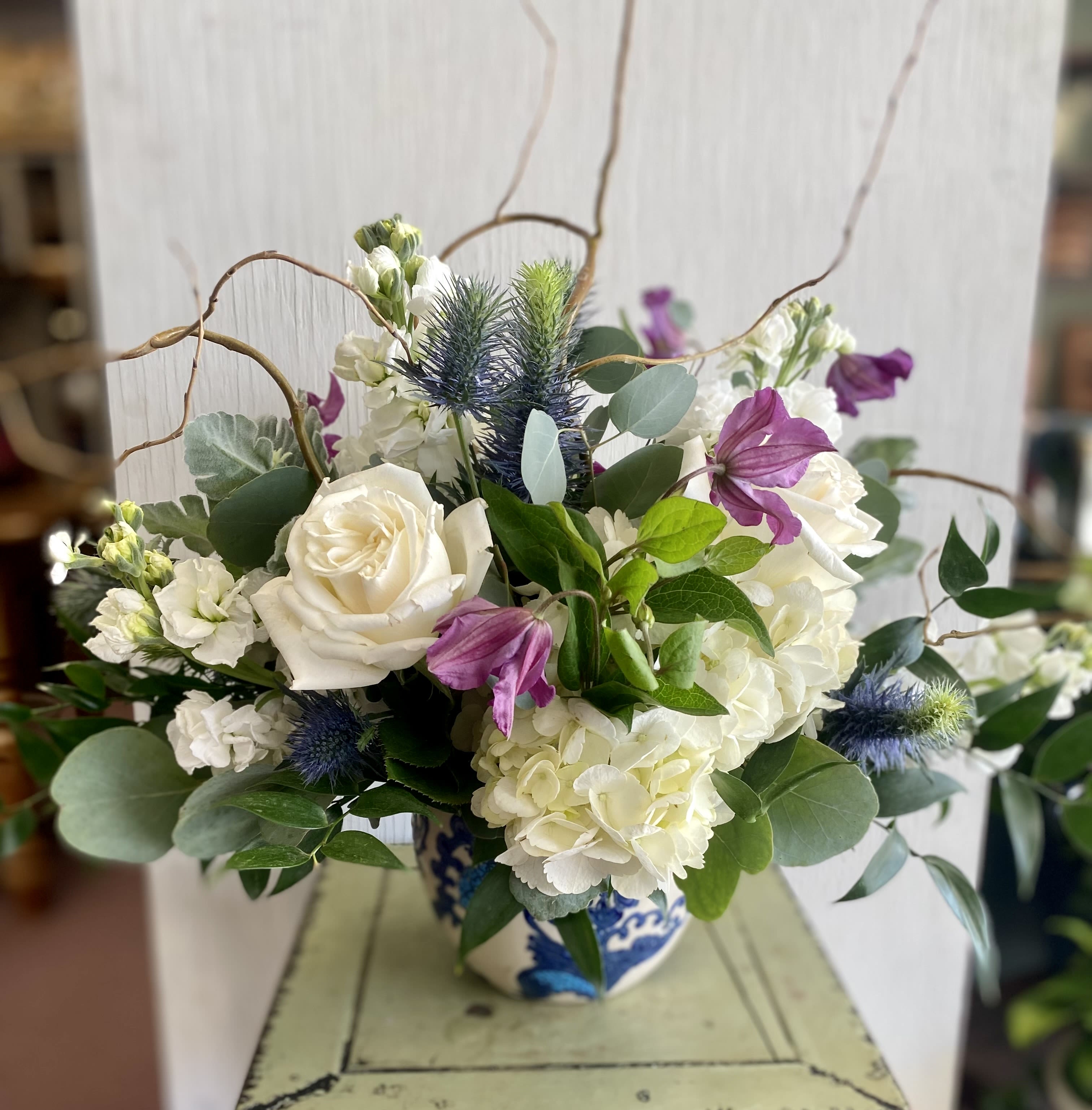 White roses and hydrangeas with purple blooms in a blue-and-white vase