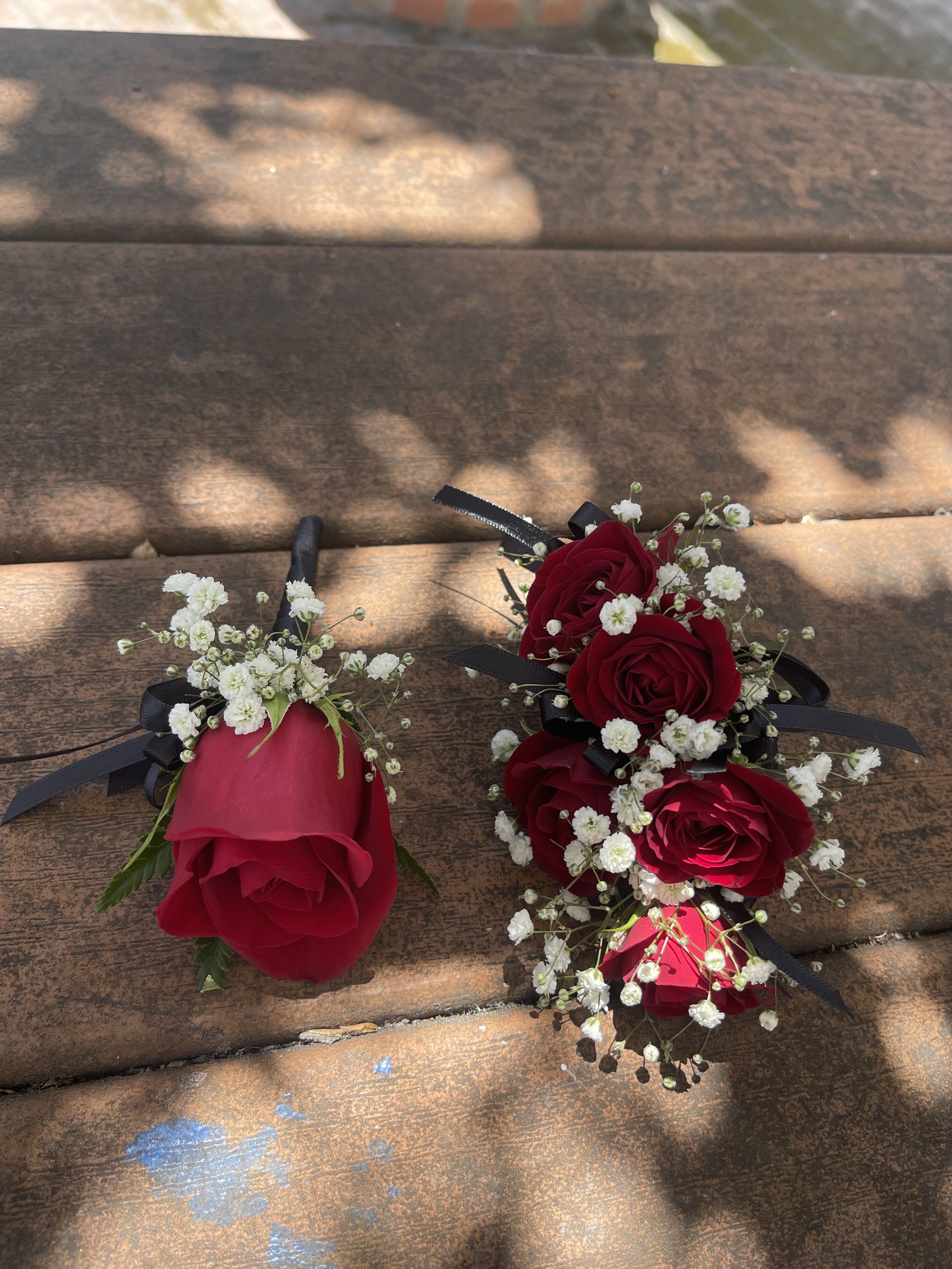 Red rose boutonnieres with baby's breath and black ribbon
