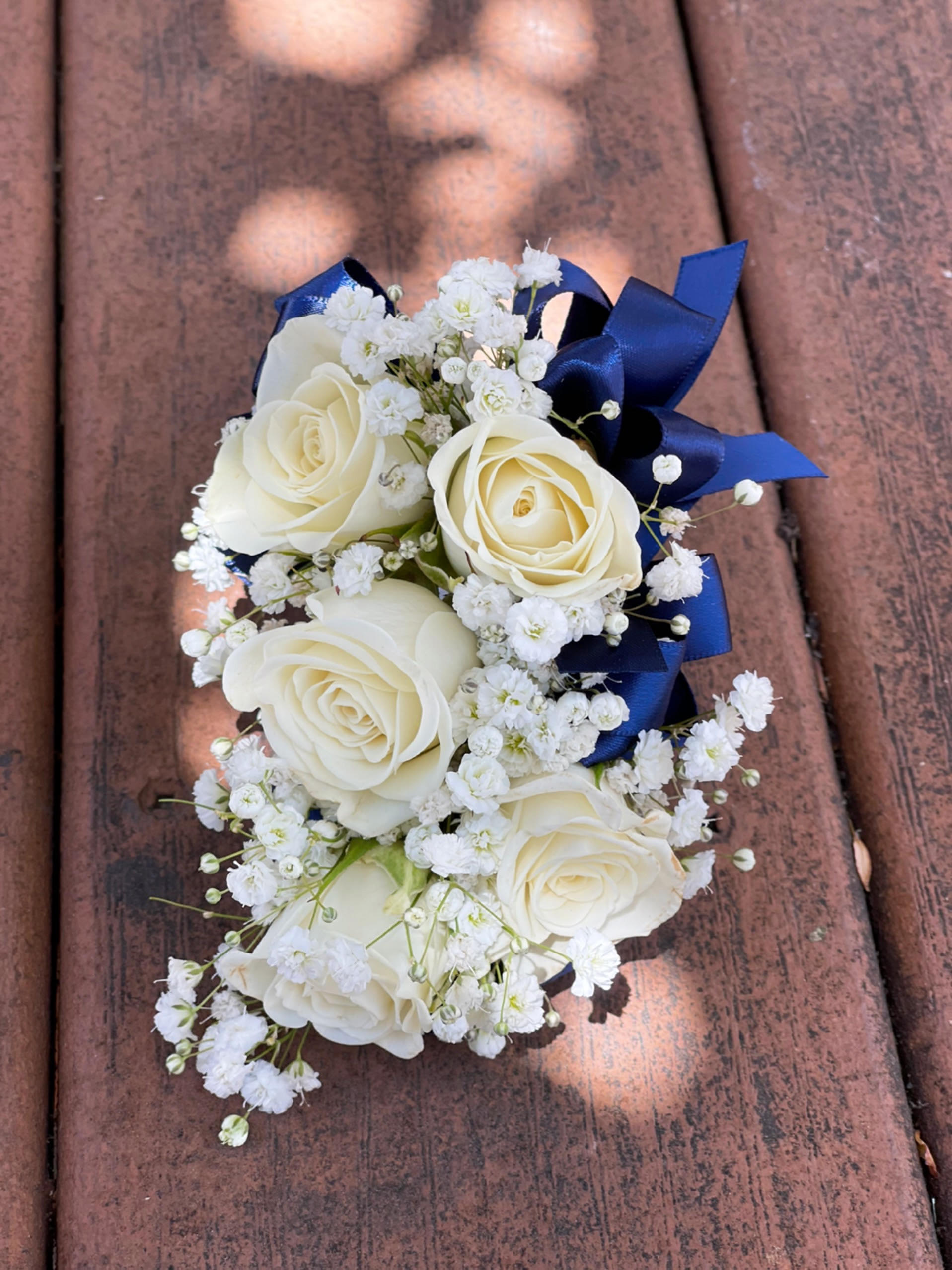 White rose corsage with baby's breath and navy ribbon