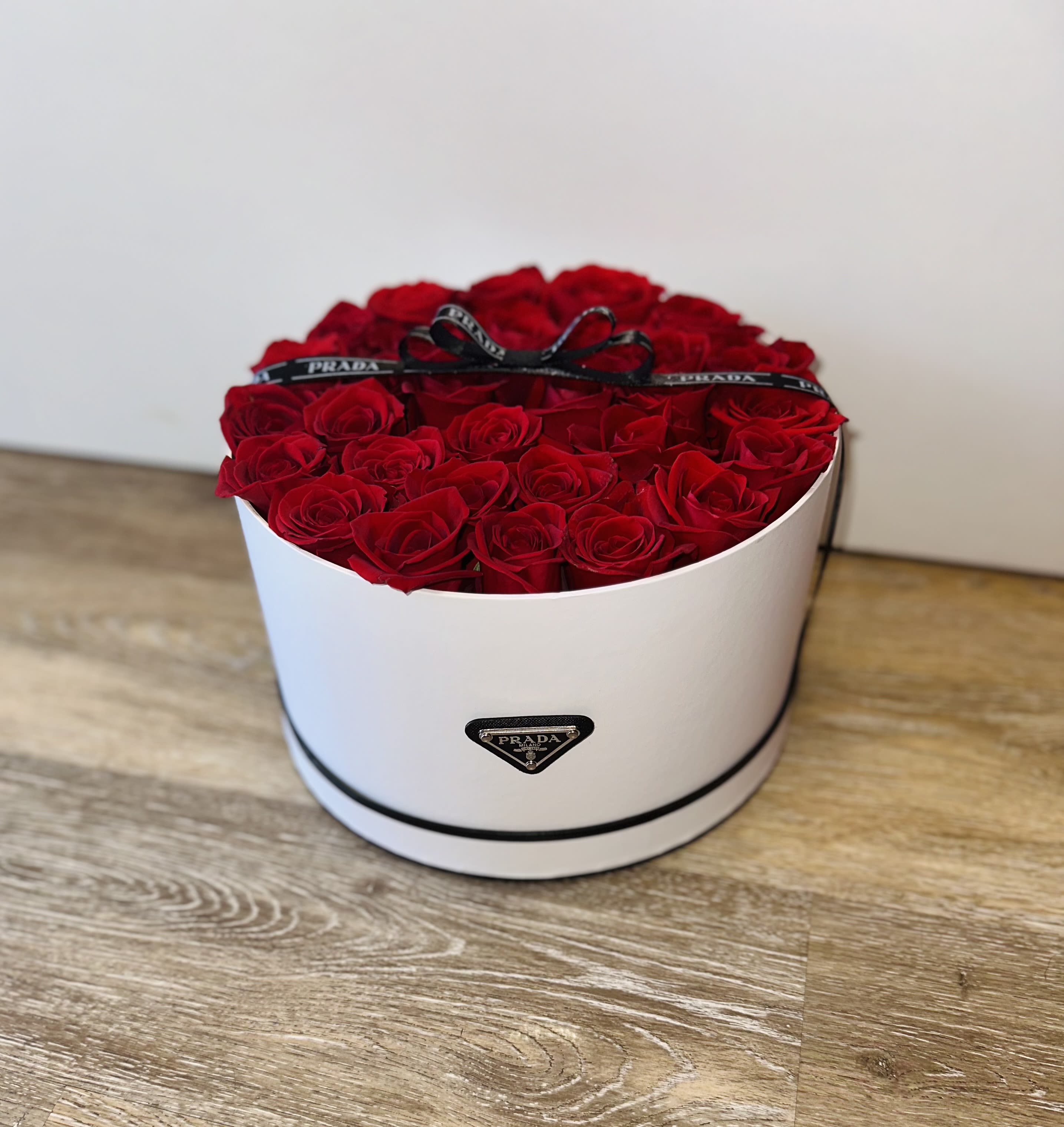 Round box filled with red roses and a black ribbon