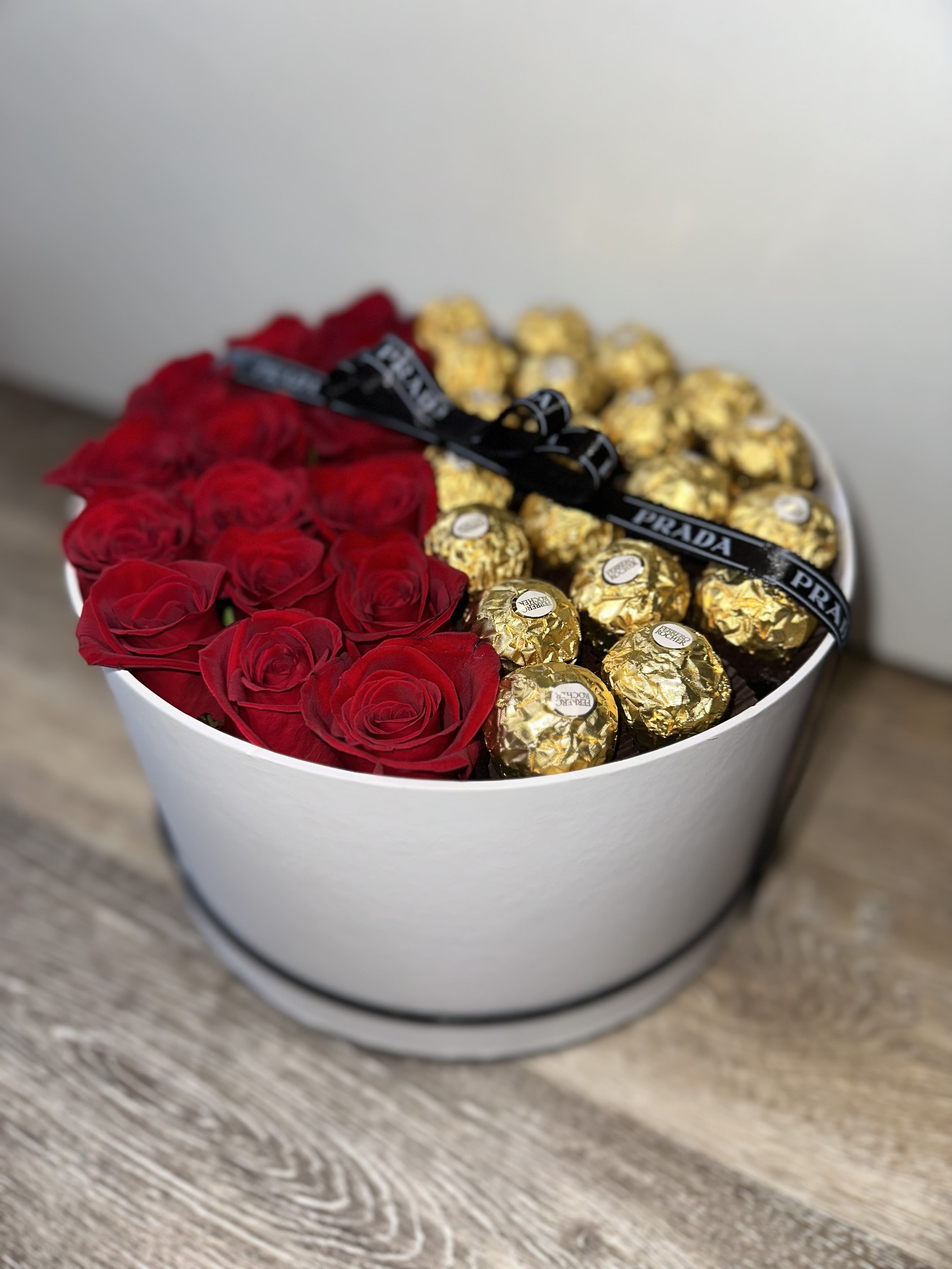 Red roses and gold-wrapped chocolates arranged in a white round box