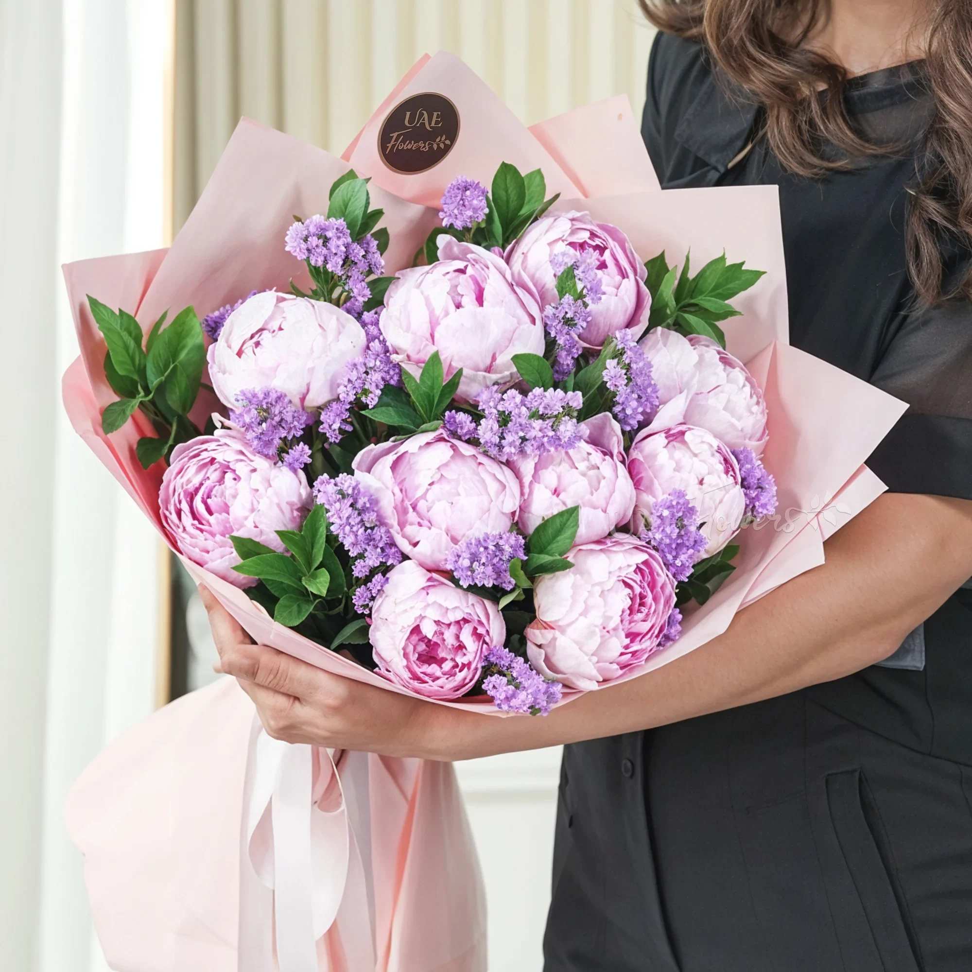 Symphony Peonies wrapped Bouquet  - Embark on a journey of blissful beauty with our bouquet featuring a delightful fusion of Pink Peonies  Delight your senses with our charming bouquet featuring 10 stems of enchanting pink peonies, accented with fillers. Adorned in a graceful pink wrapping paper and tied with lovely pink ribbons.