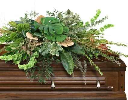 Graceful Comfort Casket Spray - Graceful Comfort embraces the peacefulness of a farewell with a woodland-inspired casket spray. Safari Sunsets mingle with verdant greens and the earthy charm of dried mushrooms. In its rustic beauty, this arrangement whispers of quiet moments and timeless memories, providing gentle comfort to those who grieve.  Includes: Casket Saddle W, Aspidistra, Baby Blue Eucalyptus, Seeded Eucalyptus, Coccullus, Curly Willow, Monstera, Myrtle, Variegated Pittosporum, Italian Ruscus, Bells Of Ireland, Green Trick Dianthus, Safari Sunset, Dried Flat Mushrooms.