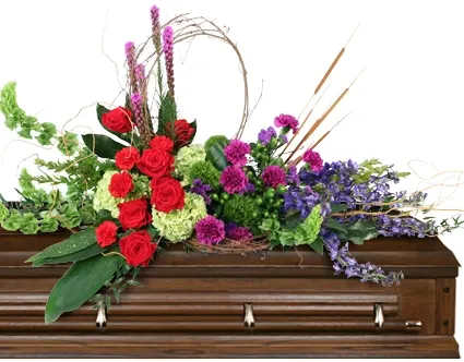 Restful Harmony Casket Spray - In a serene image of farewell, this arrangement offers peace to loved ones. Restftul Harmony graces the casket with a blend of red roses, moon carnations, purple statice, cat tails, and curly willow, offering a tranquil tribute to a life well-lived. Call us today about how to order this casket spray.  Includes: Casket Saddle W, Aspidistra, Milky Way Aspidistra, Curly Willow Tips, Fatsia, Myrtle, Israeli Rusucs, Grapevine, Mini Cat Tails, Bells Of Ireland, Red Carnations, Purple Moon Carnations, Deep Blue Delphinium, Green Trick Dianthus, Green Hydrangeas, Green Hypericum, Purple Liatris, Red Roses, Deep Purple Statice.