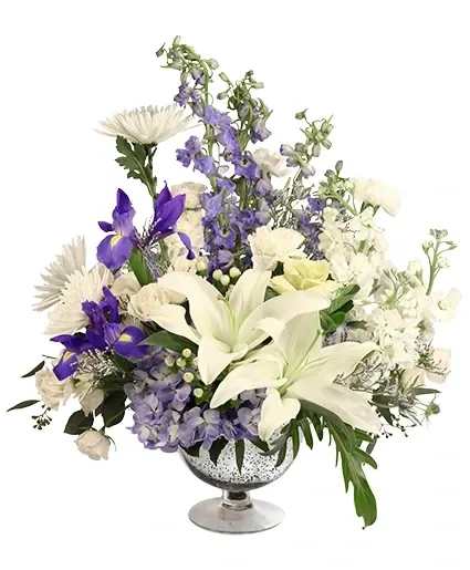 Clandestine Dreams Flower Arrangement - Soft and delicate, this stunning bouquet is a classic hit! The lovely white carnations, lilies, spray roses, and more contrast beautifully with the blue delphinium, iris, and hydrangeas, to create a truly wondrous mix. Clandestine Dreams is sure to be the highlight of any occasion!  Includes: Mercury Glass Vase,  , Seeded Eucalyptus, Misty Blue, Kale, White Carnations, Blue Delphinium , Blue Hydrangea, White Hypericum , Iris, White Lily, White Daisy Pom, White Spider Mum, White Spray Rose, White Stock.