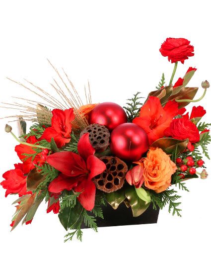 Ravishing Rich Red Christmas Arrangement - If you are looking for a stunning centerpiece, Ravishing Rich Red has you covered! With red gladiolus, lilies, ranunculus, and Free Spirit roses, this design is sure to bring the season's greetings to any table. Send these jolly flowers to someone who loves to decorate for the holidays!  Includes: Black Rectangular Design Container, Lotus Pods, Red Christmas Ornaments, Greens: Magnolia Leaves (Painted Gold), Explosion Grass, Flowers: Red Gladiolus, Free Spirit Roses, Burgundy Lilies, Red Ranunculus, Red Hypericum.