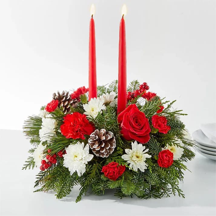 Holiday centerpiece with red candles, roses, and white flowers