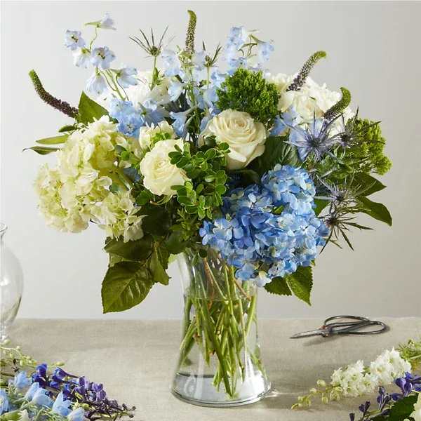 Blue and white floral arrangement in a clear glass vase