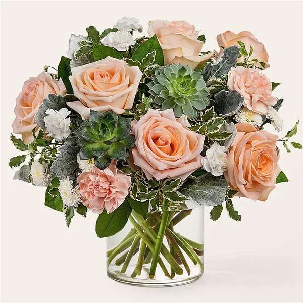 Peach roses and succulents in a clear glass vase