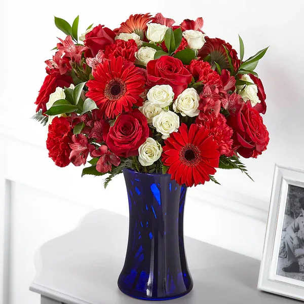 Red and white mixed bouquet in a blue glass vase