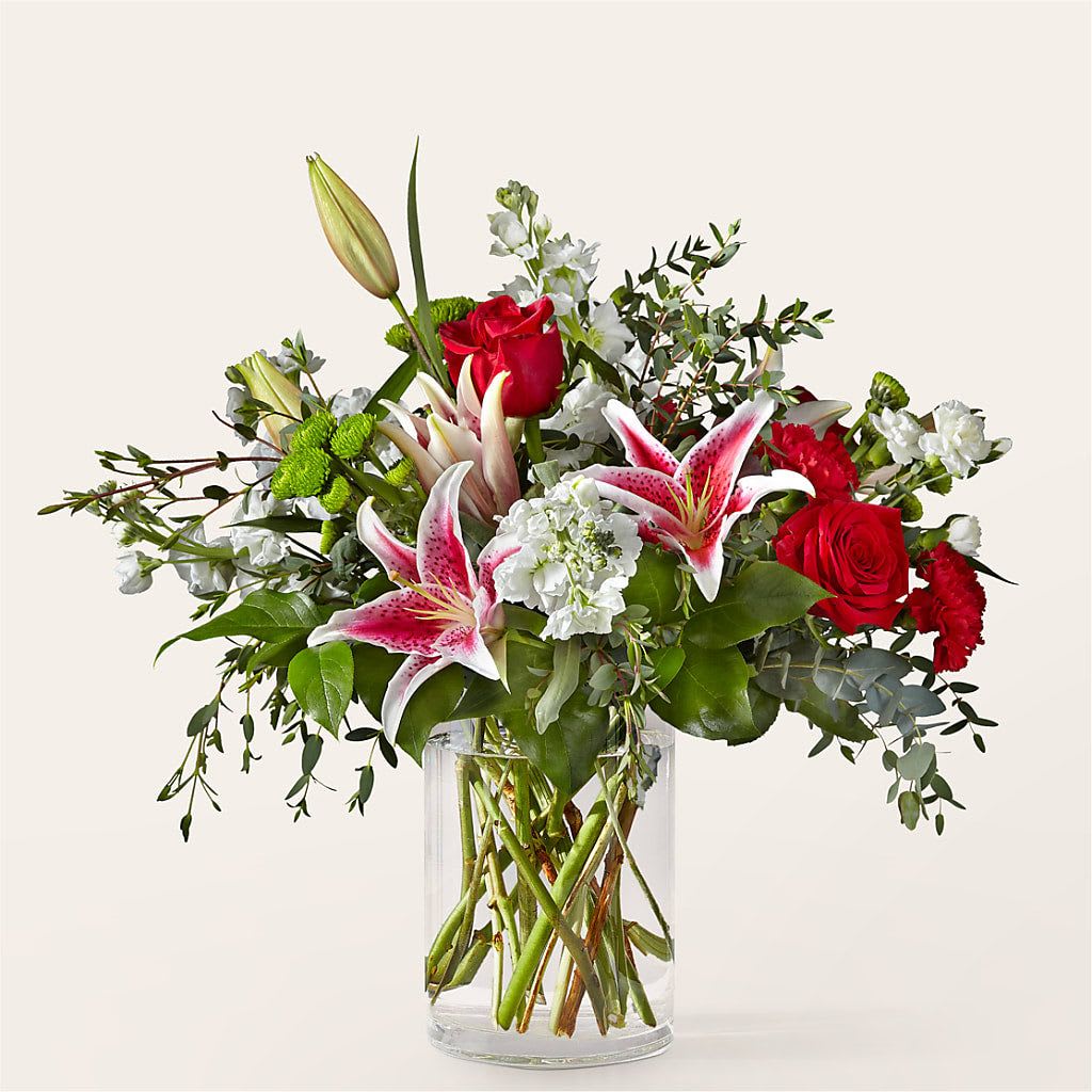 Bouquet of red roses and pink lilies in a clear glass vase