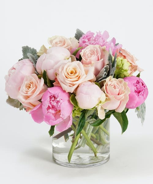 Pink and blush bouquet of roses and peonies in a clear glass vase