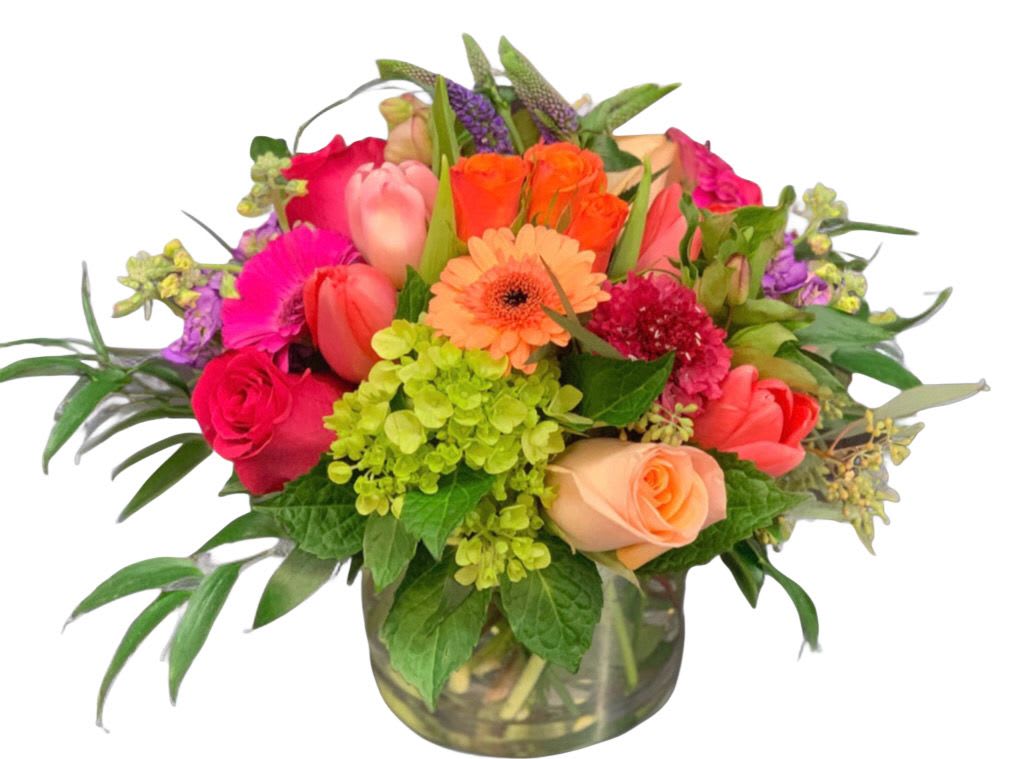 Bright mixed arrangement of roses, tulips, gerbera daisy and hydrangea in a clear glass vase