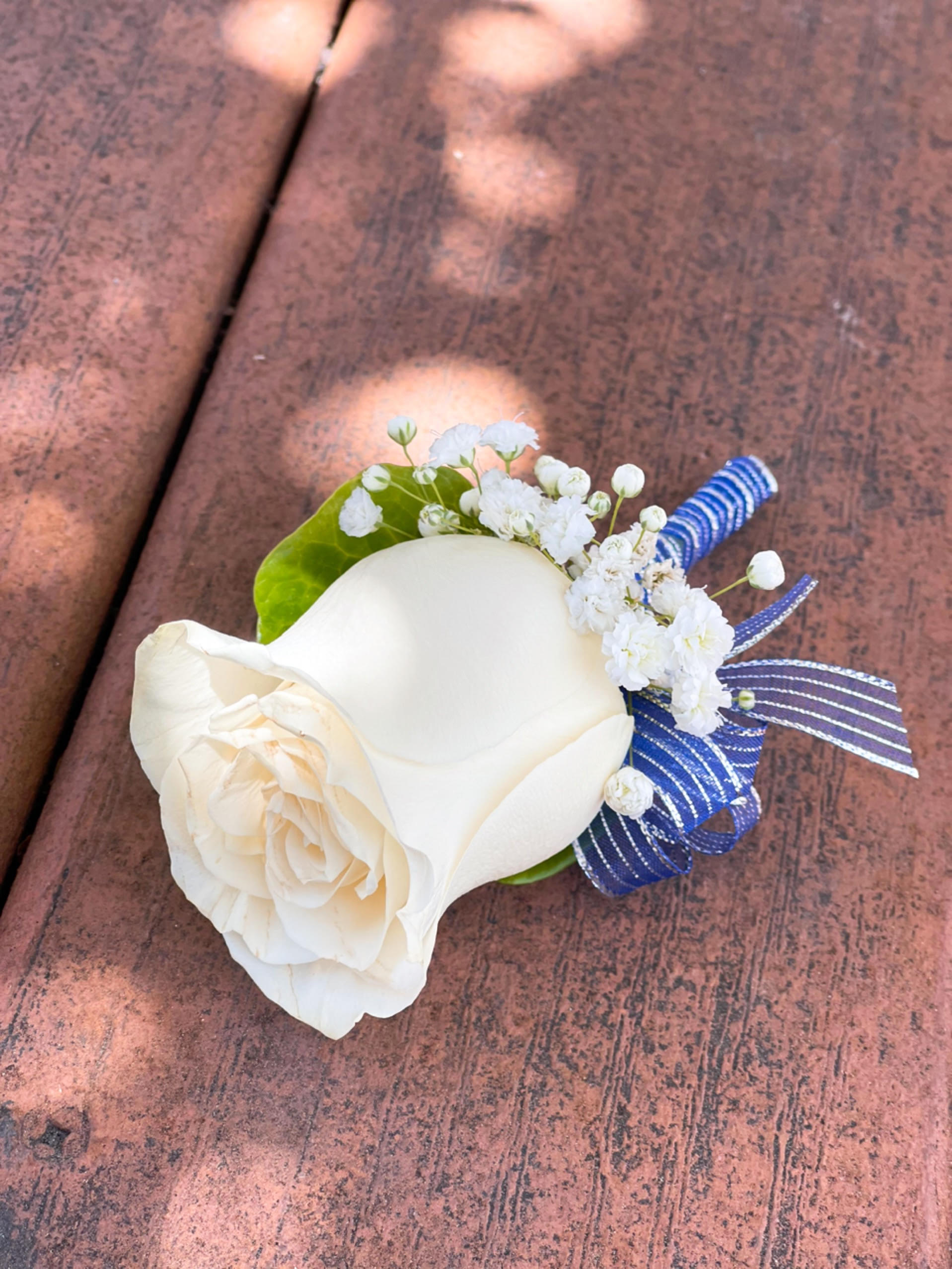 White rose boutonniere with baby's breath and blue ribbon accents