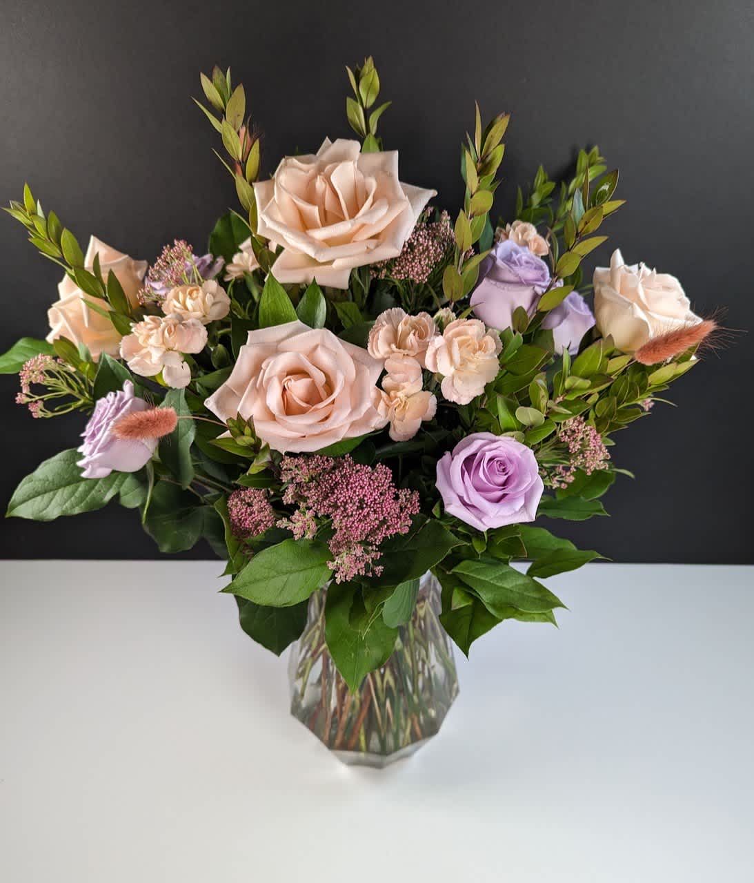Bouquet of blush and lavender roses in a clear glass vase