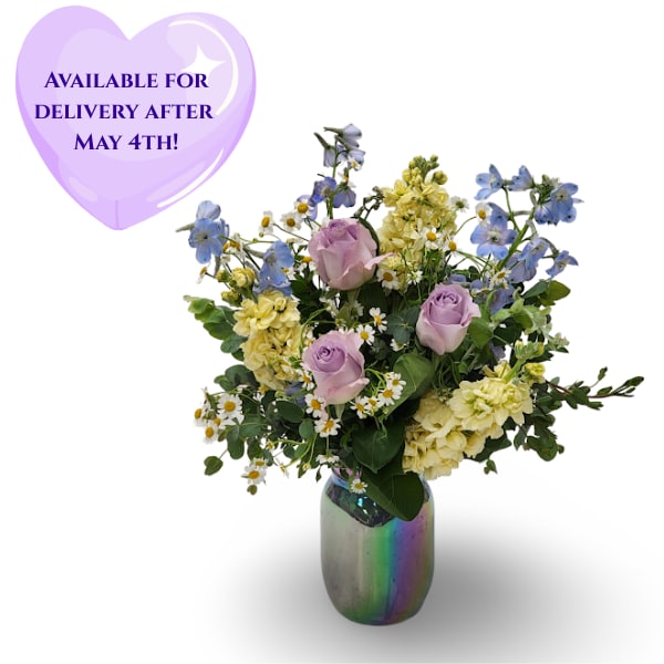 Sweet Pastels - Soft and soothing like a summer breeze, Sky Bloom brings together calming blue Bella Donna, elegant lavender roses, sunny yellow stock, and cheerful chamomile. Arranged in a glowy iridescent blue mason jar, this bouquet feels like a little jar of light and love — perfect for brightening someone’s day.  Approximately 18" x 14" x 12"