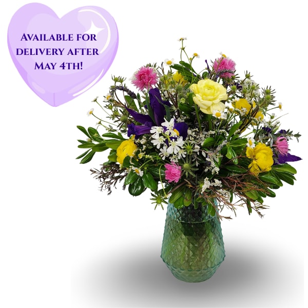 Spring Fields - Select this lovely wildflower arrangement in a blue bubble glass vase. Brimming with a fresh and unique wildflower look. Filled with iris, ranunculus, paper daisies, lavender, thistle, orlaya, and accented with chamomile and misty.  Approximately 18" by 13".