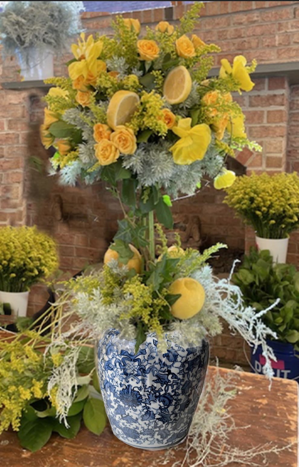 Yellow floral arrangement in a blue-and-white ceramic vase with citrus slices.