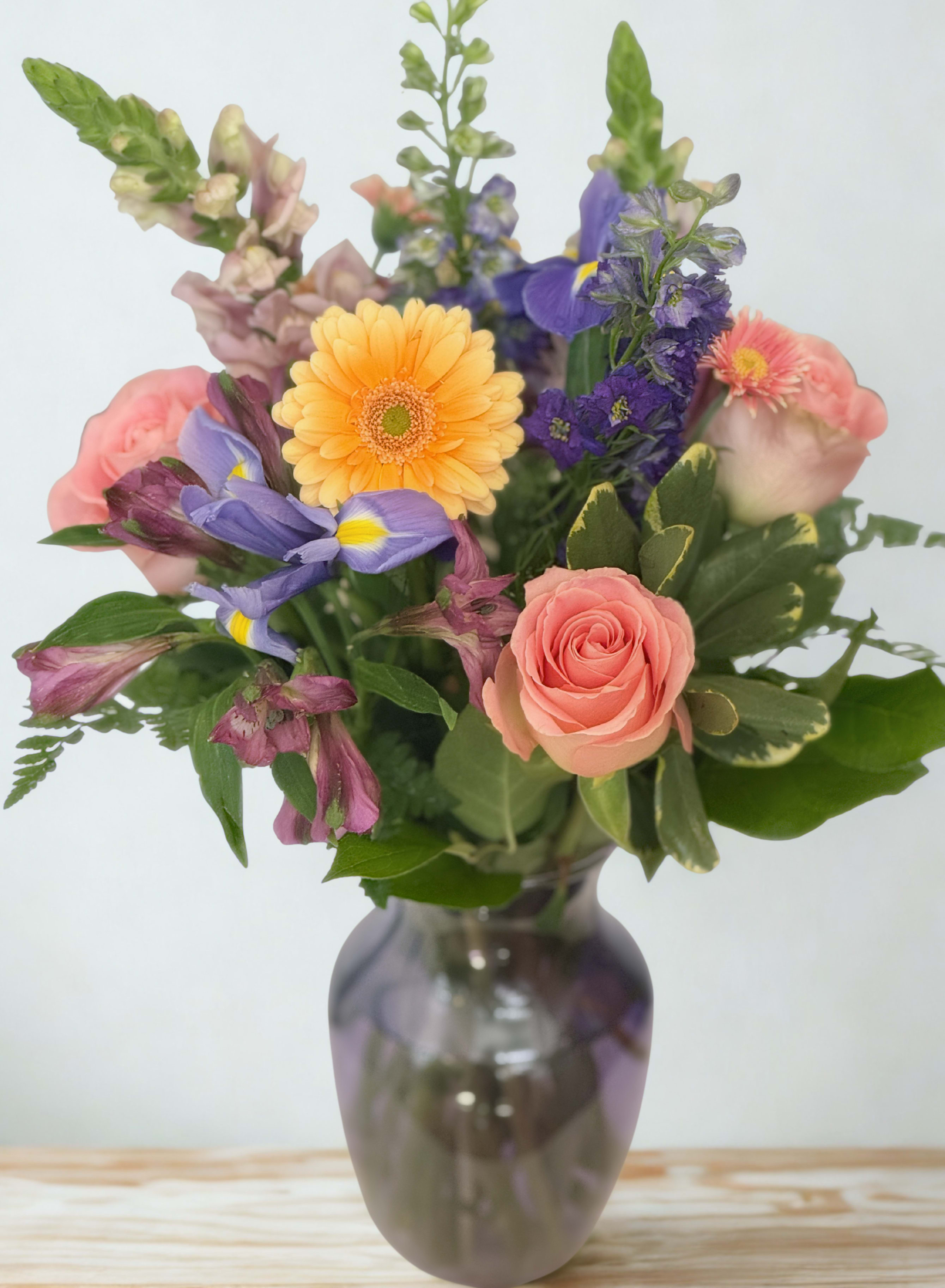 Mixed bouquet of pink, purple, and yellow flowers in a glass vase