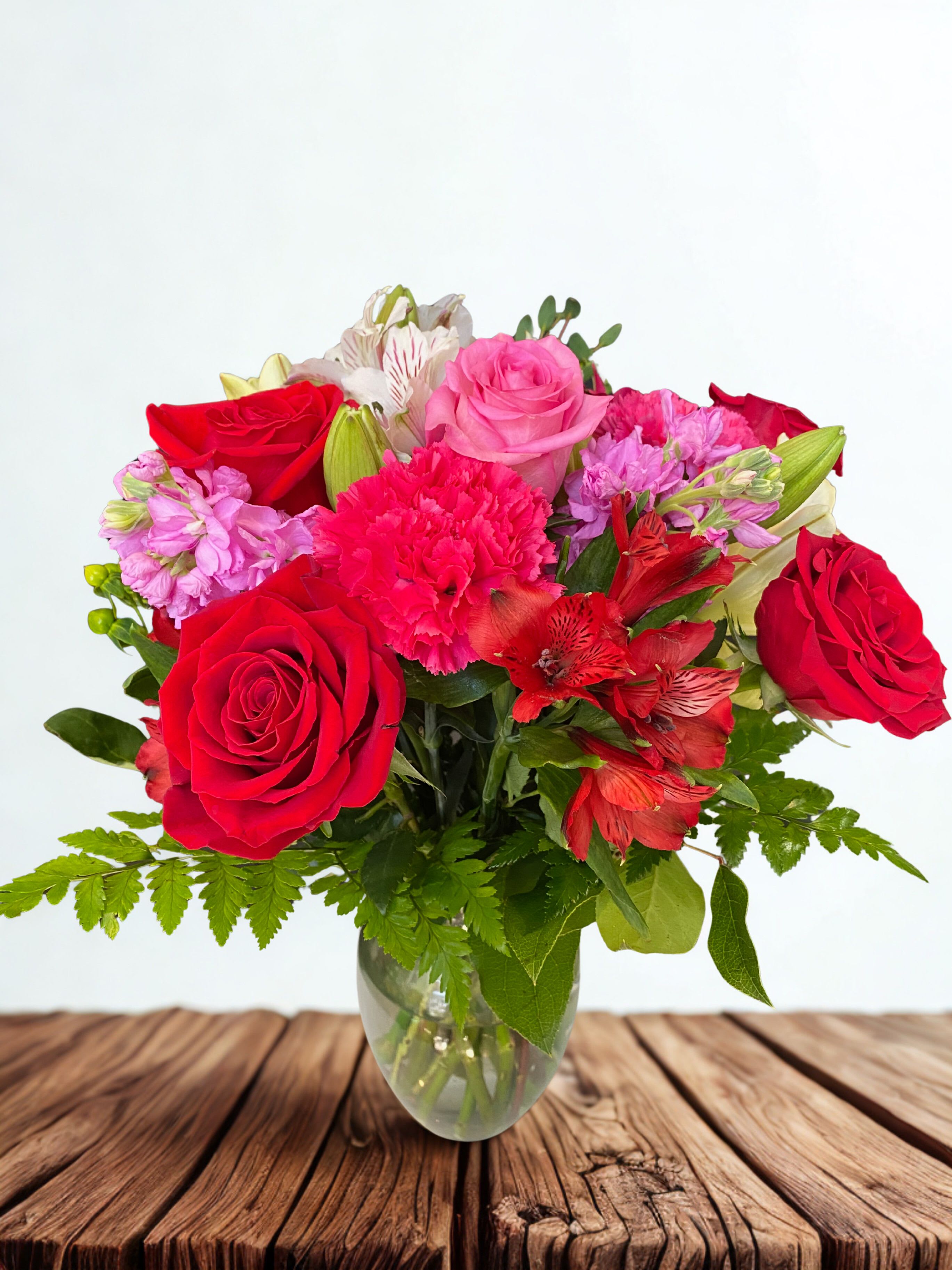 Bouquet of red and pink roses with carnations in a glass vase