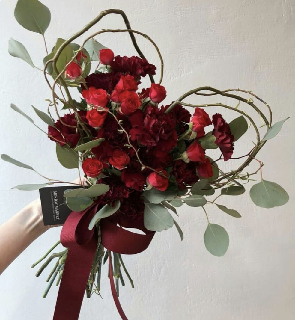 Red roses and dark red carnations in a hand-tied bouquet with ribbon