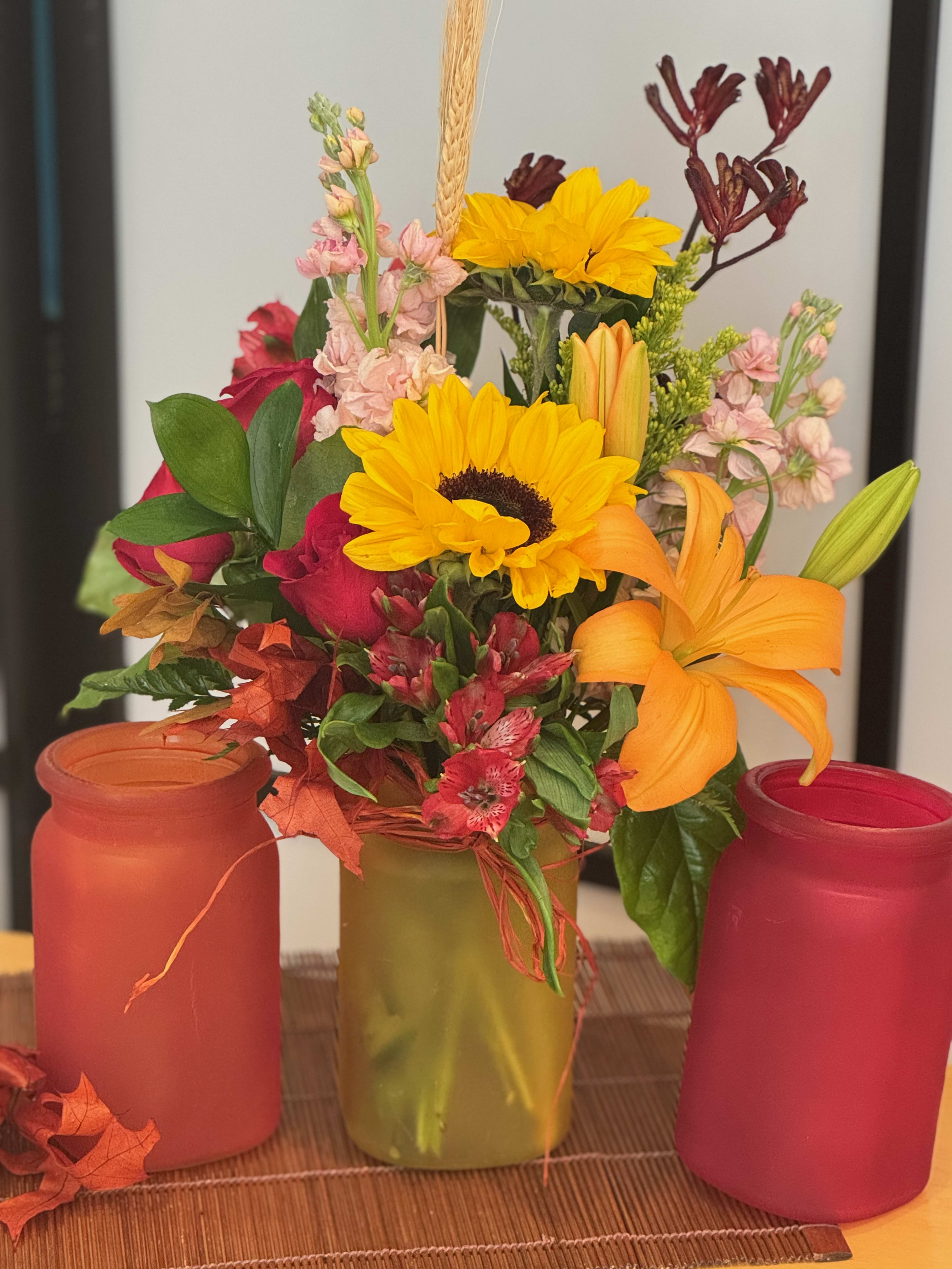 Mixed bouquet with sunflowers, lilies, roses, and pink filler flowers in a vase