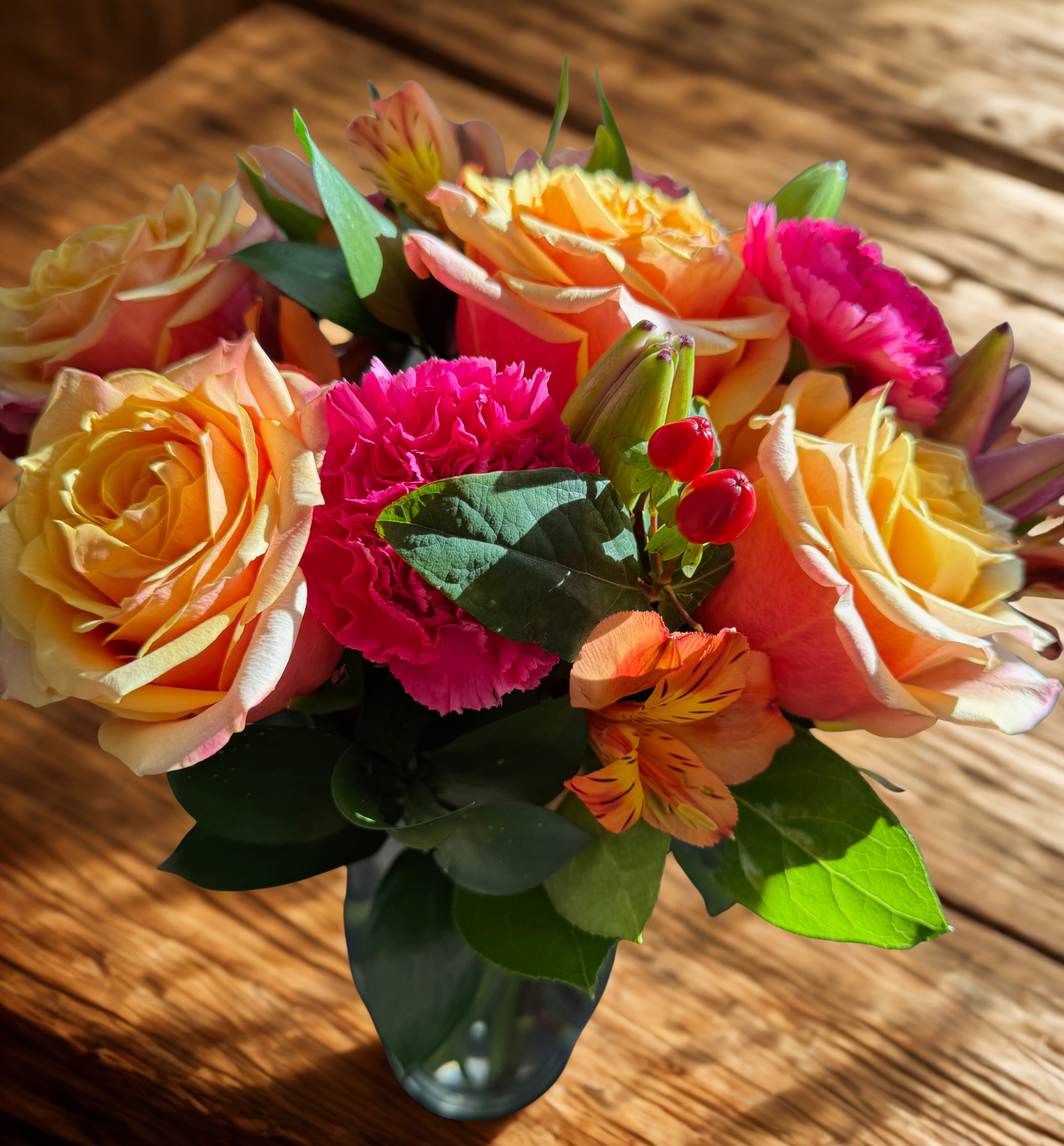 Bouquet of peach roses and pink carnations in a glass vase