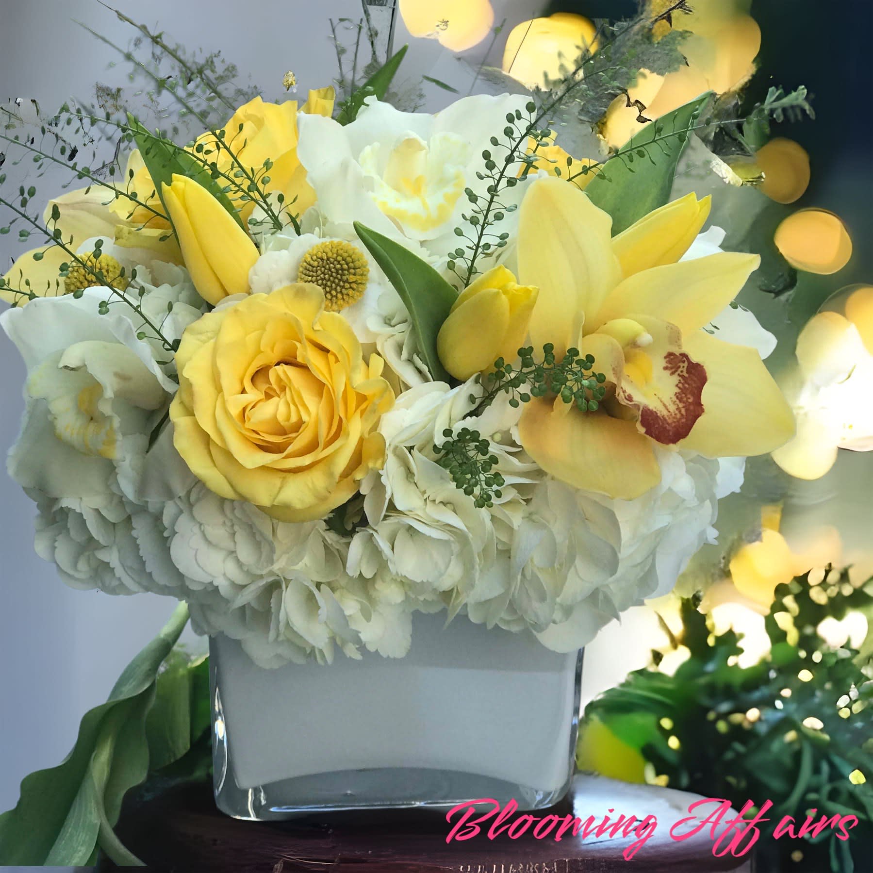 Yellow and white floral arrangement in a square glass vase