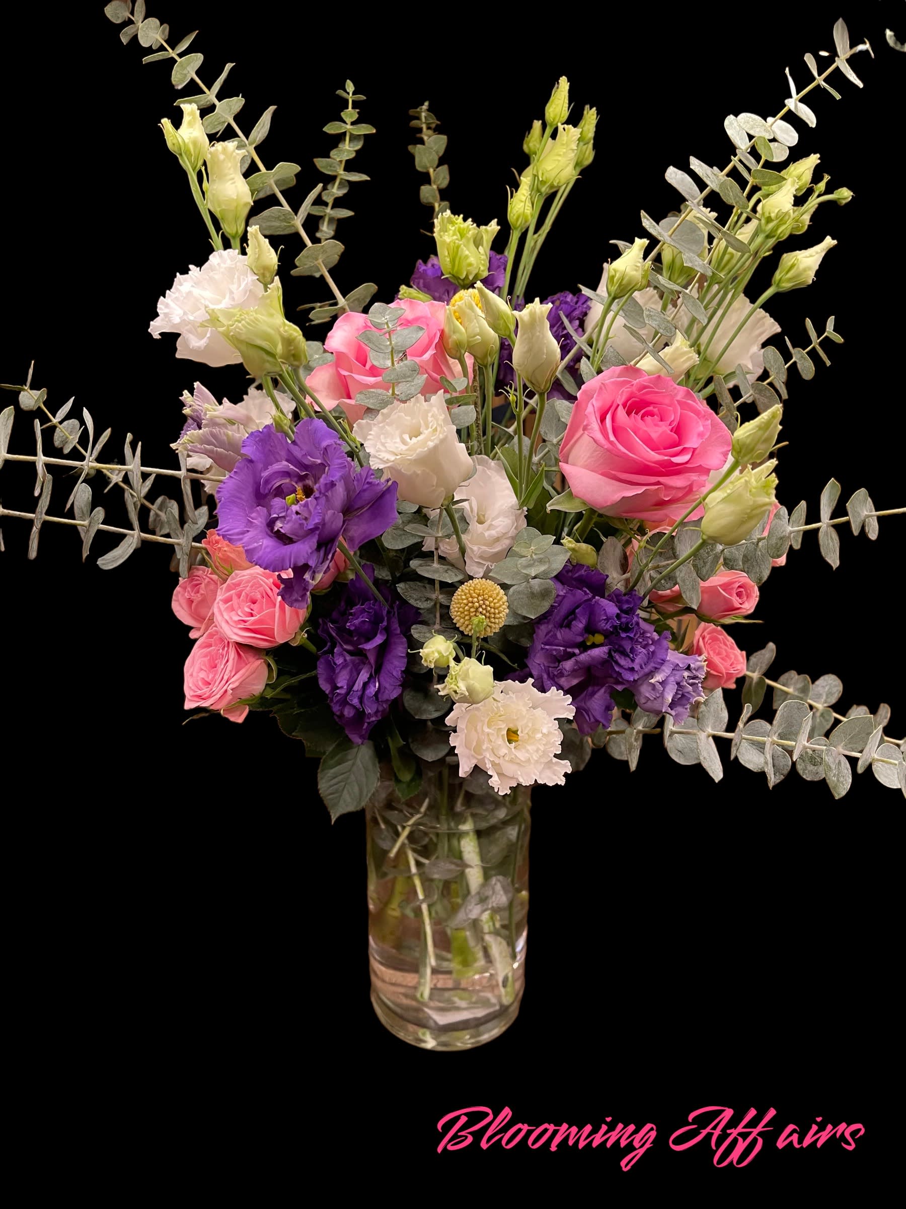Pink and purple bouquet in a glass vase with eucalyptus