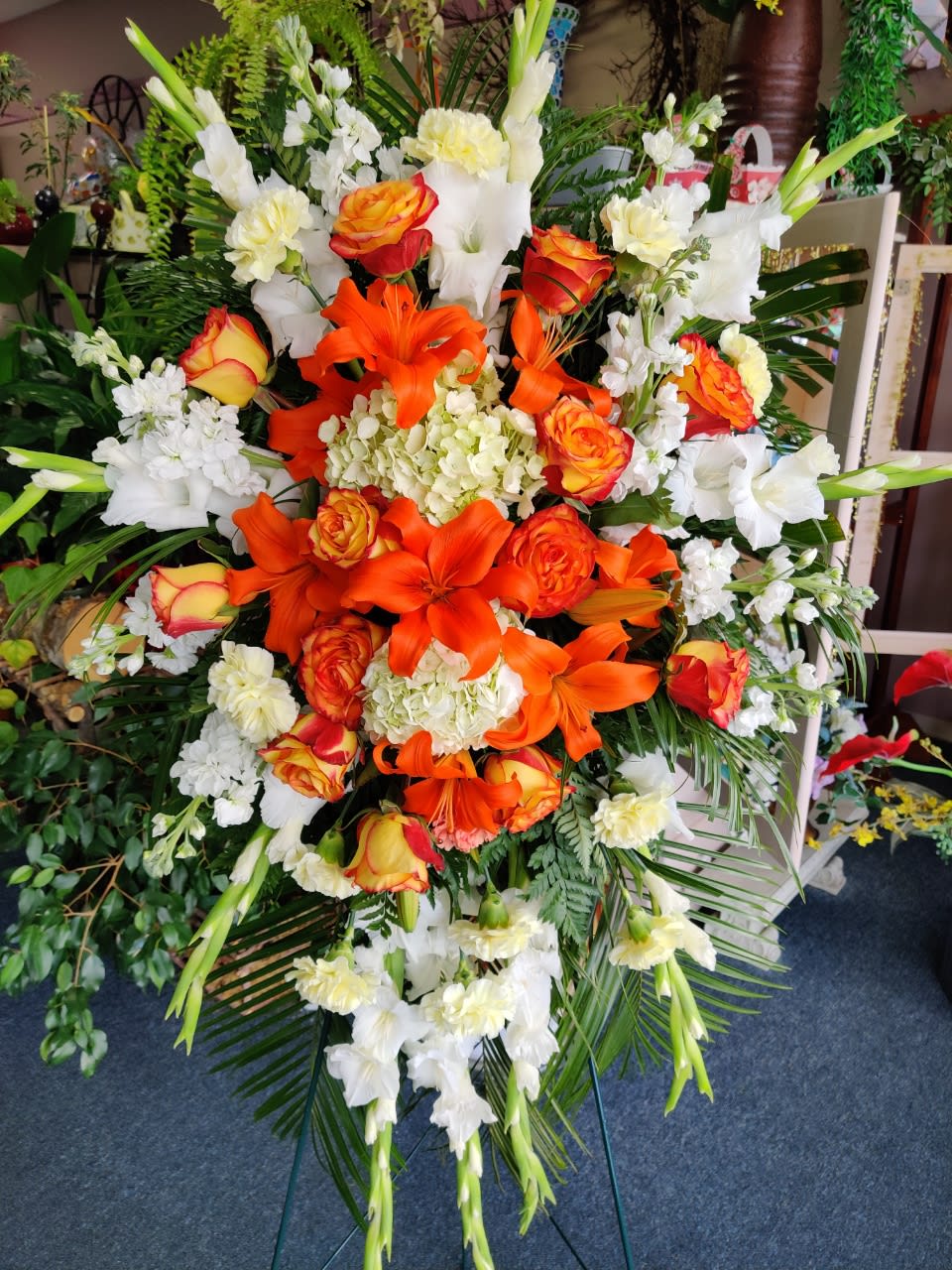 Large orange and white floral standing spray with roses and lilies