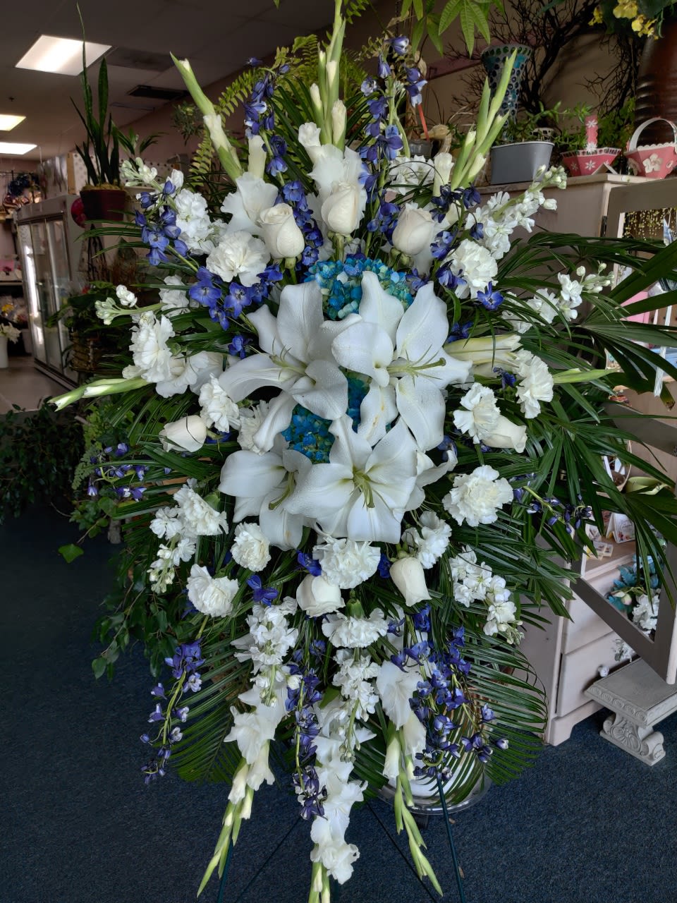 Large white and blue funeral spray with lilies and orchids