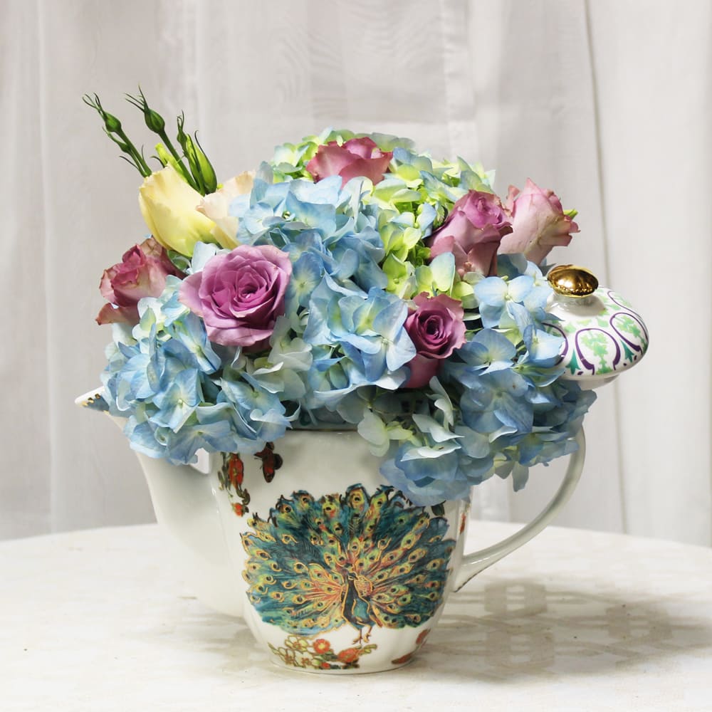 Pastel flower arrangement in a decorative teacup vase.