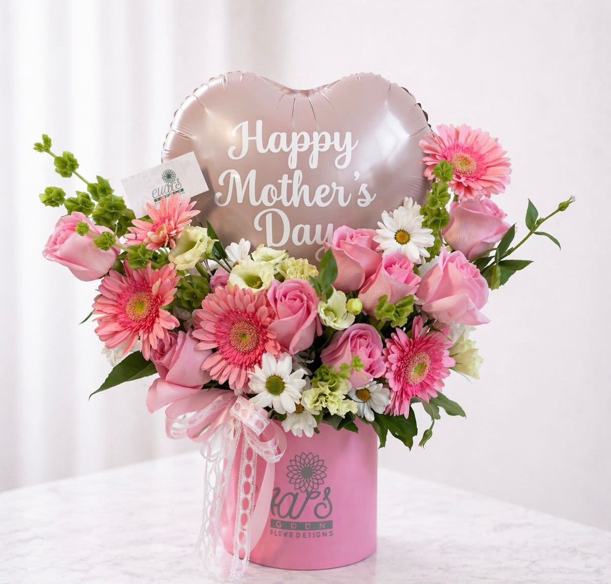 A Mom's Heart - Beautiful floral box arrangement with pink Gerber daises, pink roses, bells of Ireland, daisies, and queen lace. This arrangement also comes with a heart-shaped balloon. 