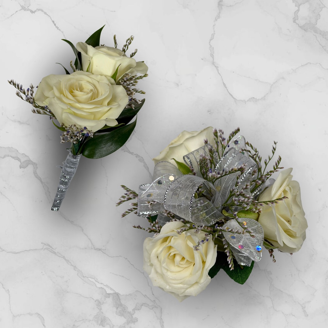 Opal 3 Rose Combo - Make ordering prom flowers a breeze this year with our Opal 3 Rose Combo! This combo comes with our Opal Boutonniere - With Wrap and our Opal 3 Rose Corsage, perfectly matched together to make a stunning, coordinating look.  The Opal 3 Rose Corsage features three cream-white roses gathered into a compact wrist corsage create a quietly elegant accessory for prom, with delicate purple-tipped filler, white sheer sequined ribbon and white faux shimmering leaves for added dazzle and shine. Finished with fabric leaves and a shimmering white lace wristlet, this corsage is a lovely choice to make prom night memorable.  The Opal Boutonniere - With Wrap features two creamy ivory roses, with small limonium filler blooms surrounding the roses, and dark green leaves tucked in beneath to give contrast and depth, so the person wearing it will look polished and truly cared for.