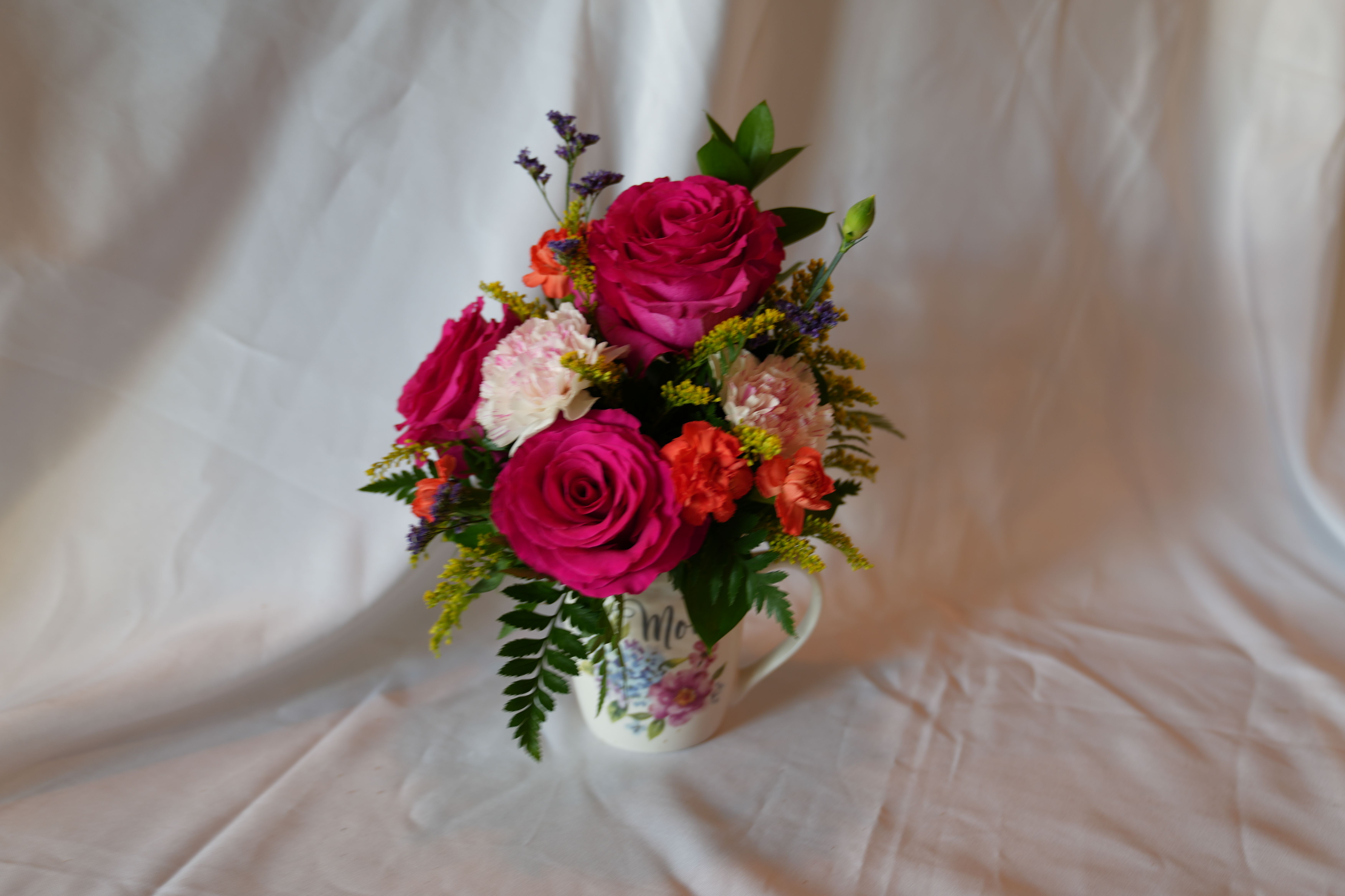 Mom’s Morning Blooms - This arrangement is designed to arrive ready to enjoy and the ceramic mug becomes a keepsake long after the stems fade. For best longevity, refresh the water every other day and recut stems if possible; it's the kind of little surprise that brightens mornings and lingers as a warm reminder.
