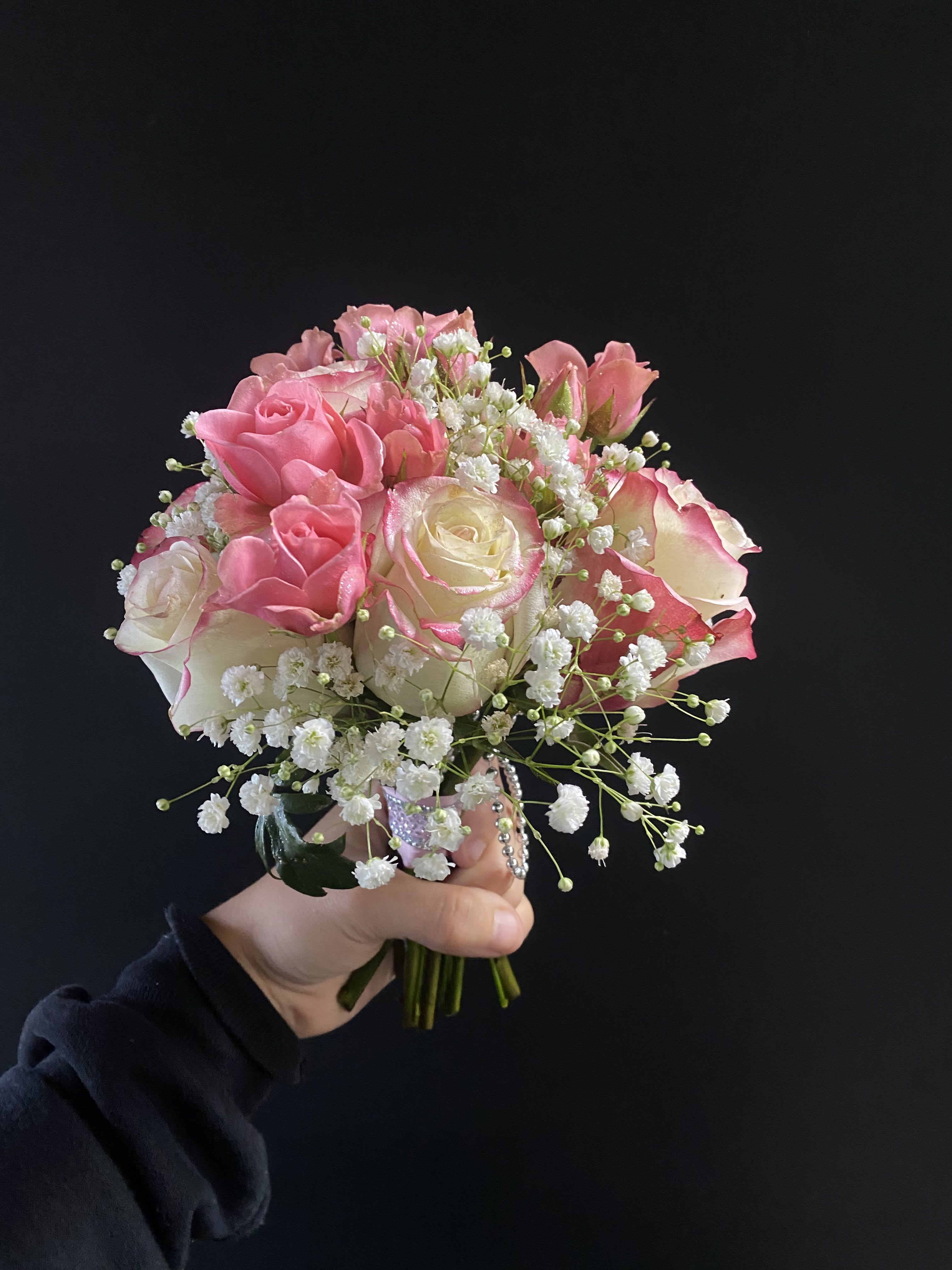 Handheld bouquet of pink and white roses with baby's breath