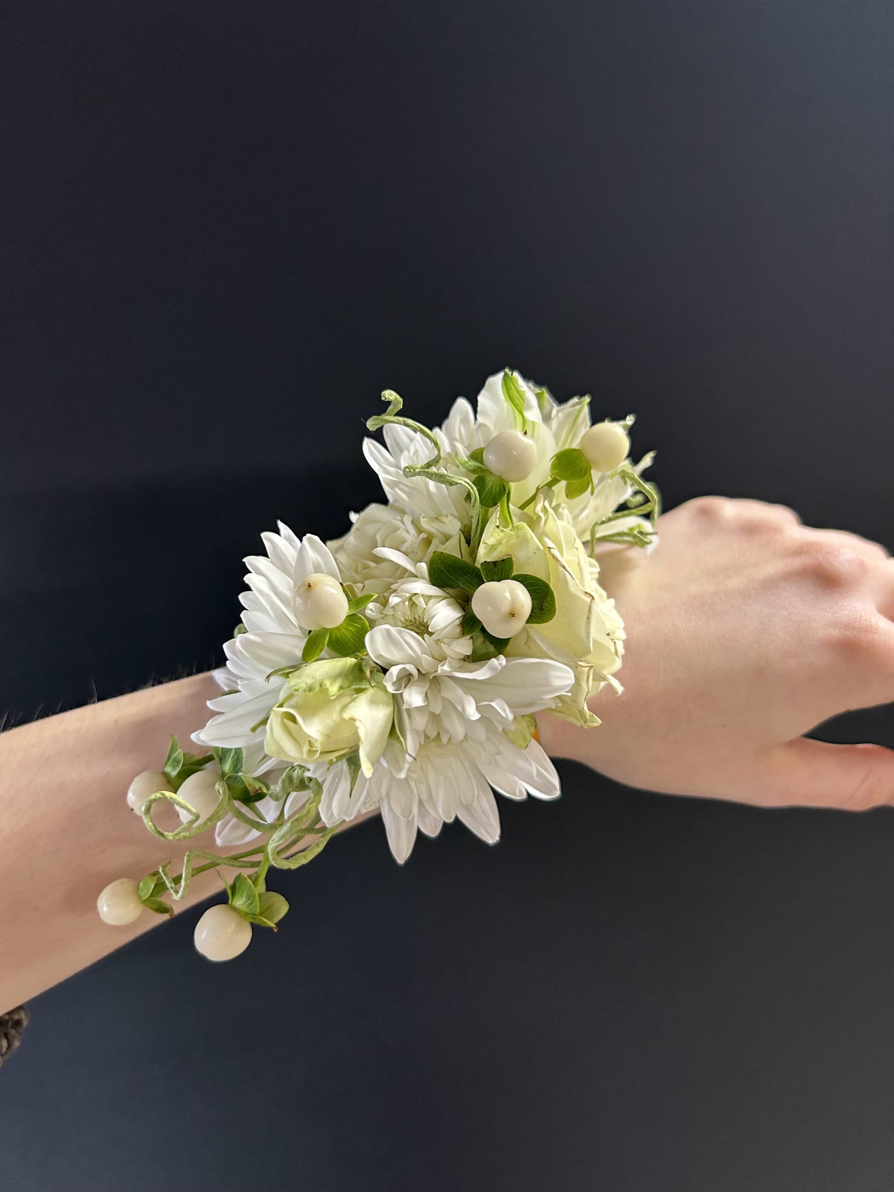 White floral wrist corsage with small berries on a person’s wrist