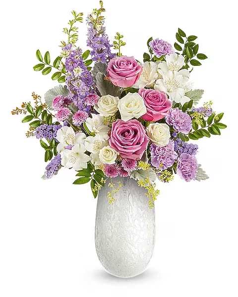 Prism Petals Bouquet - Celebrate Mom with the Prism Petals Bouquet, a radiant mix of pink, lavender, and ivory blooms beautifully arranged in the Amelia Vase. This elegant art glass keepsake adds soft shimmer and a heartfelt Mother's Day touch. The Prism Petals Bouquet is a graceful Mother's Day floral arrangement featuring lavender roses, white spray roses and alstroemeria, lavender carnations and larkspur, lavender button spray chrysanthemums, and lavender sinuata statice, accented with dusty miller, huckleberry, and seeded eucalyptus, delivered in the Amelia Vase.  