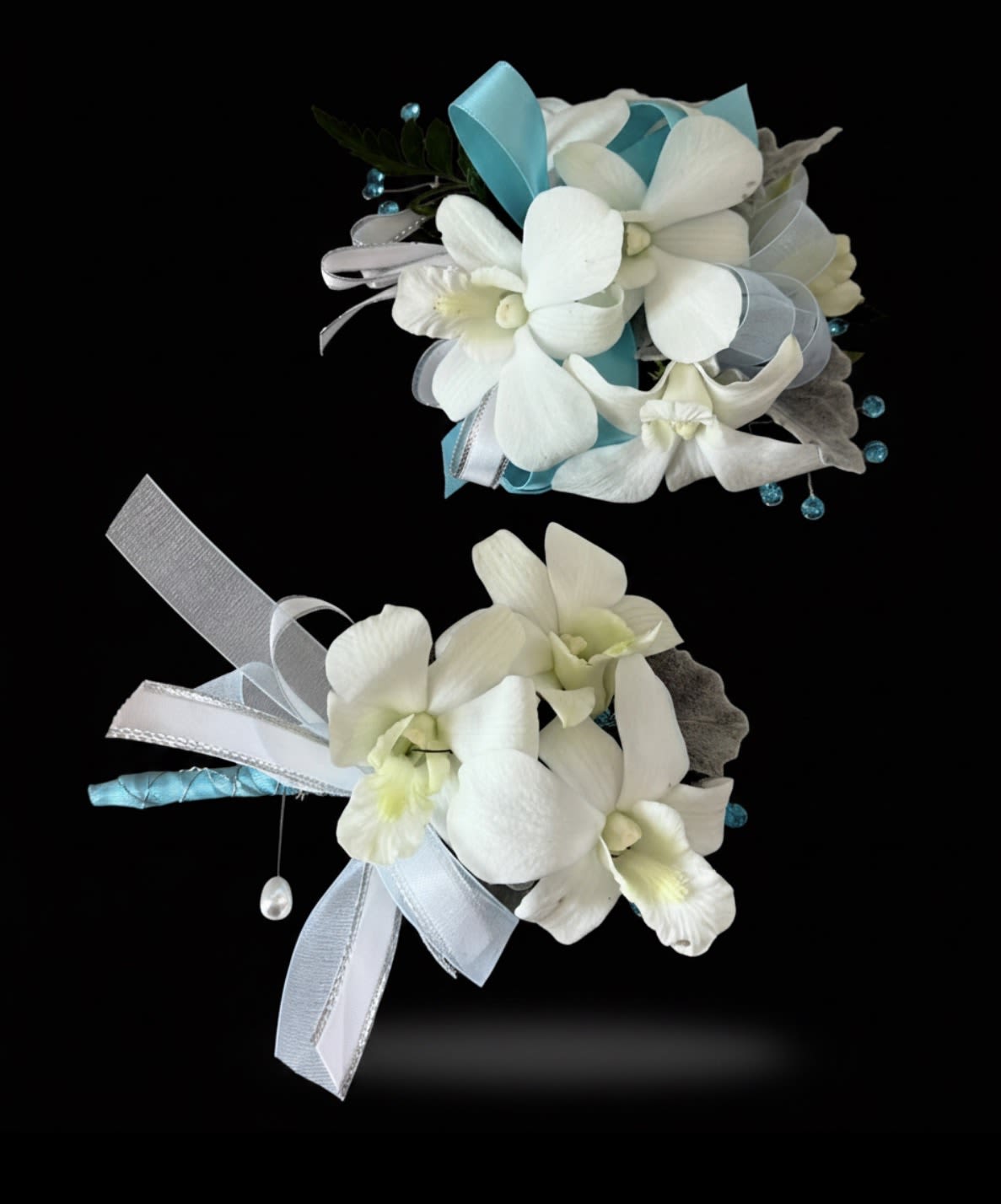 A matching set of white dendrobium orchid corsage and boutonniere set  - A matching set of white dendrobium orchid corsage and boutonniere featuring teal ribbon and rhinestone accents.