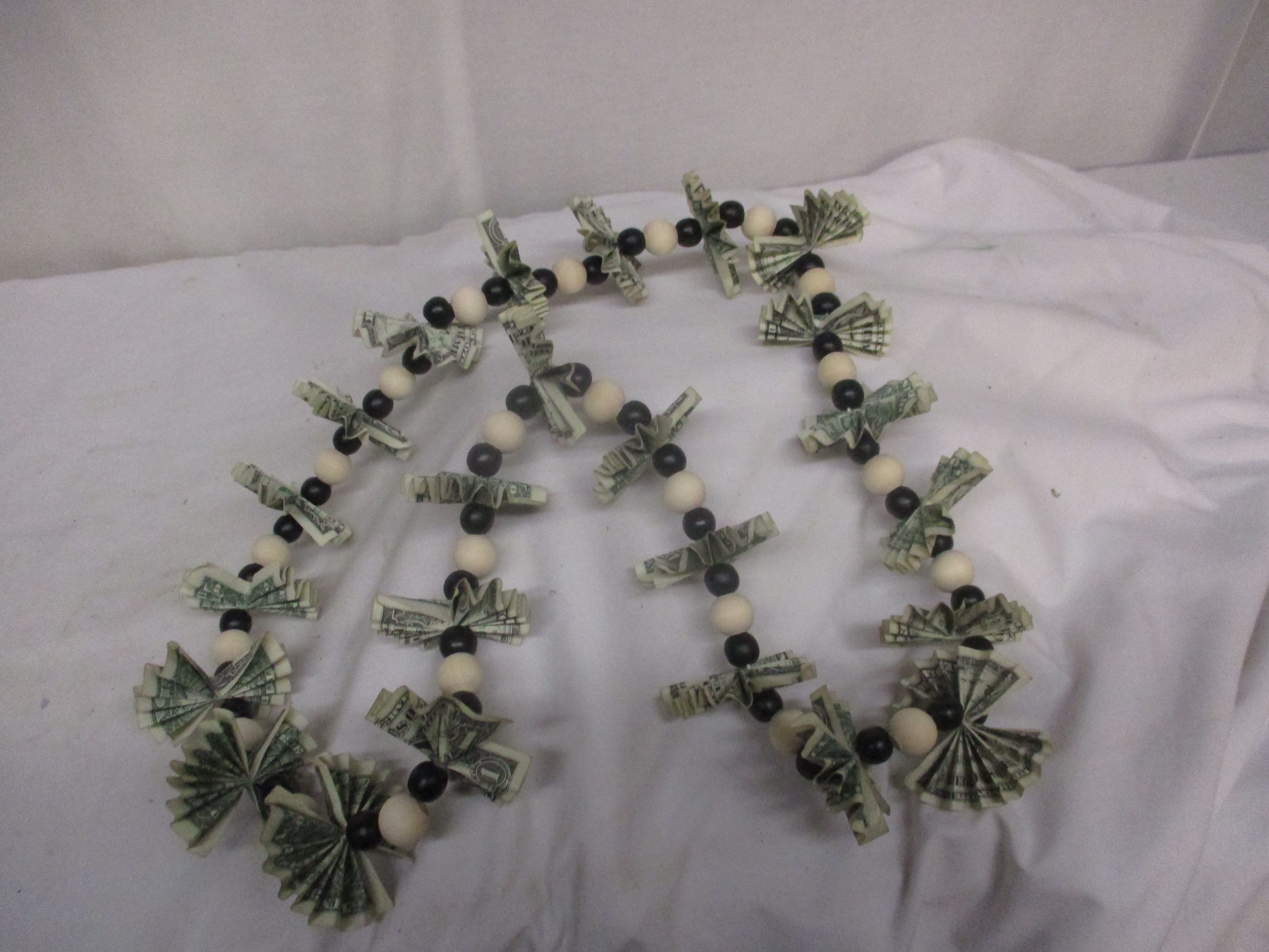 Beaded garland with folded dollar bills on a white cloth